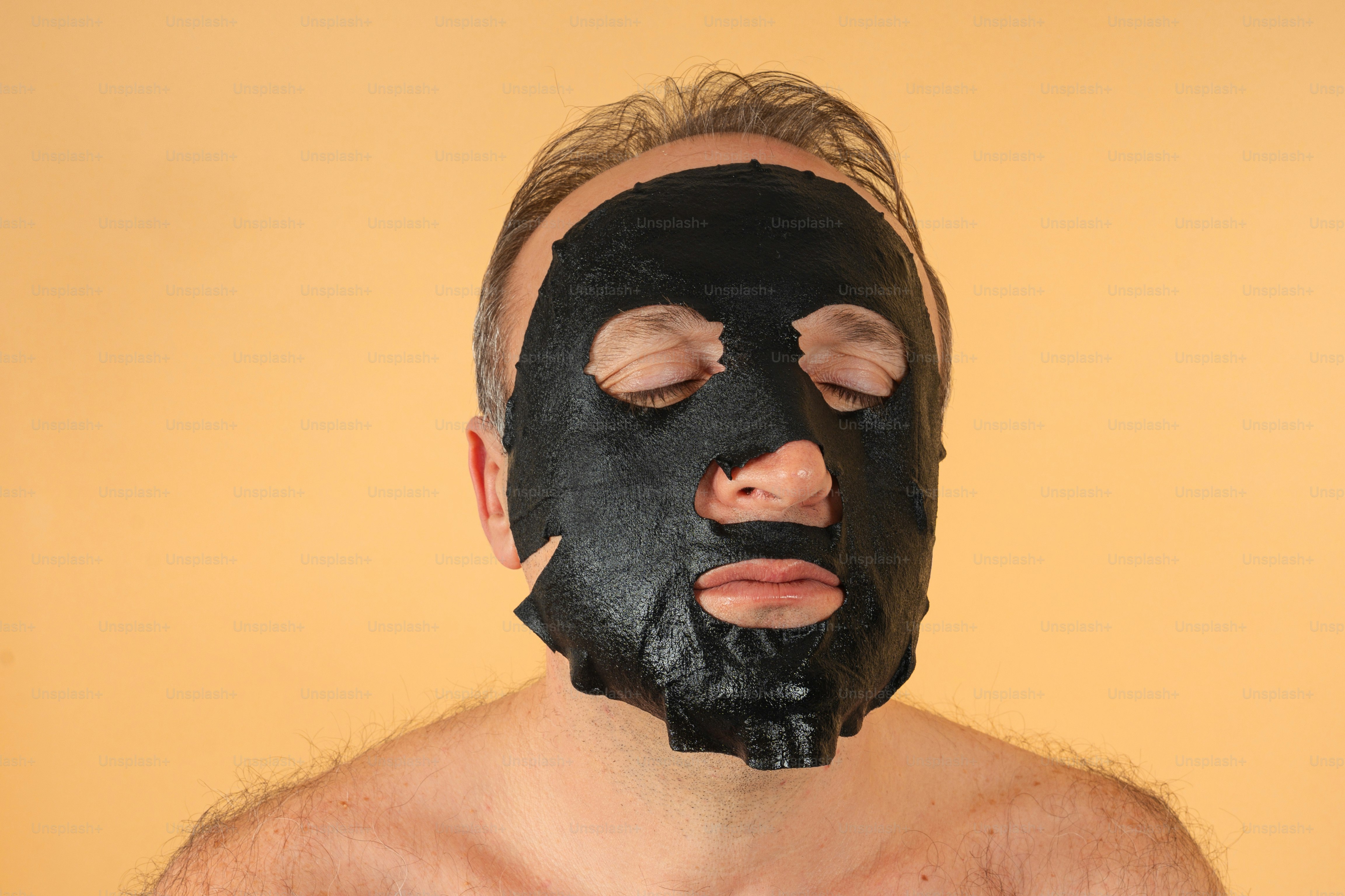 Hombre con máscara facial negra sobre fondo naranja