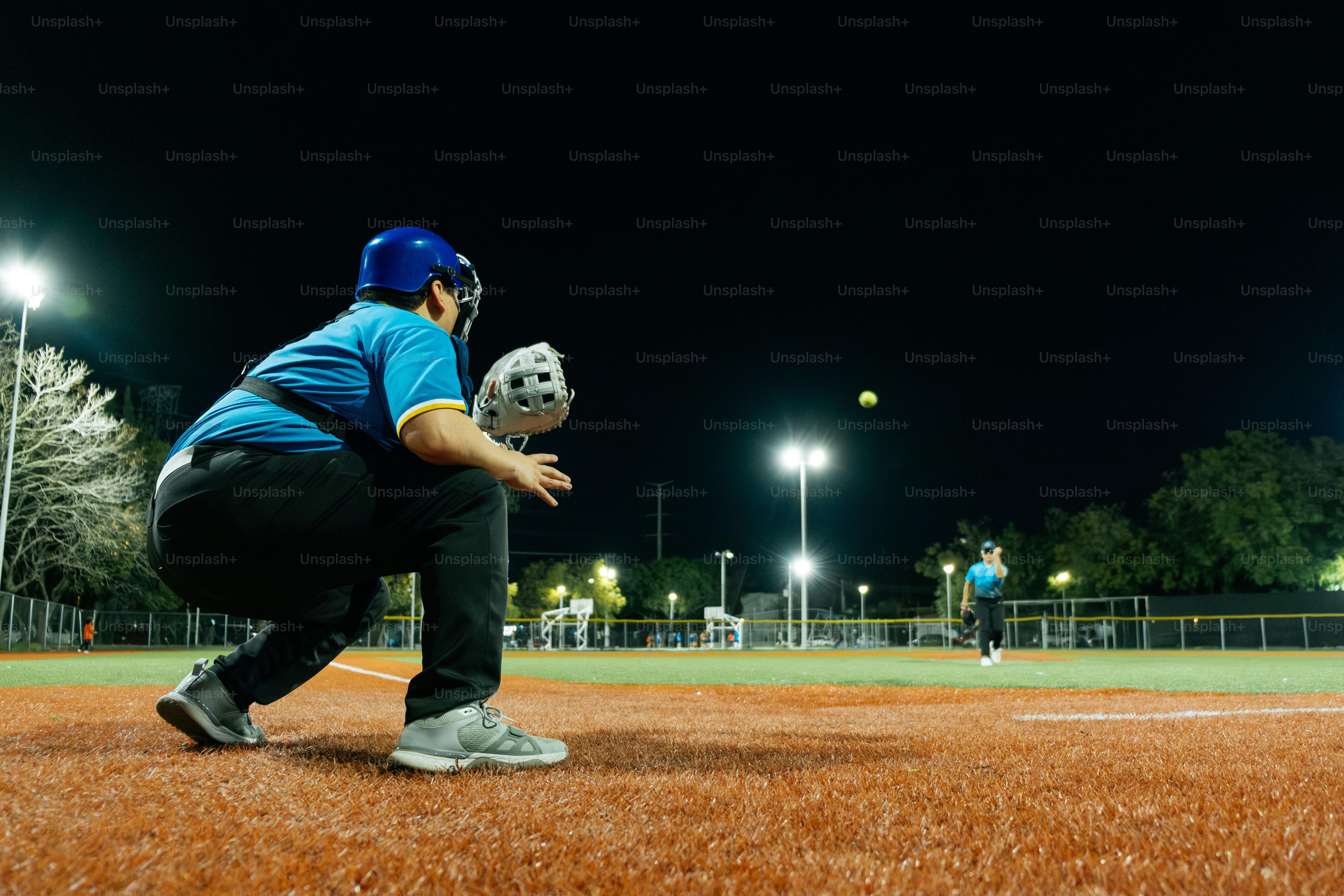 Receveur prêt à recevoir un lancer lors d’un match de baseball en soirée.