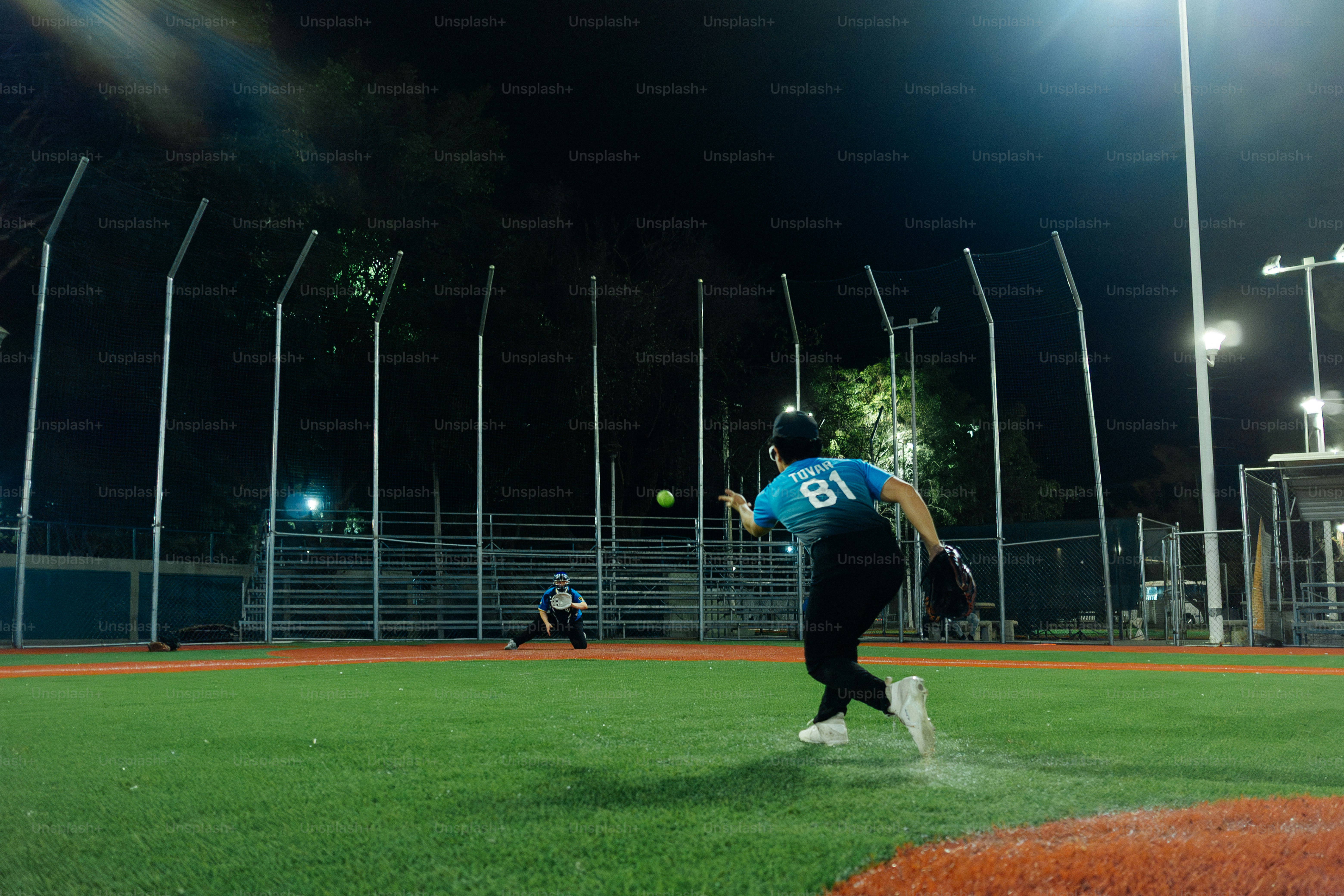 Joueuse de softball lançant une balle sur le terrain la nuit
