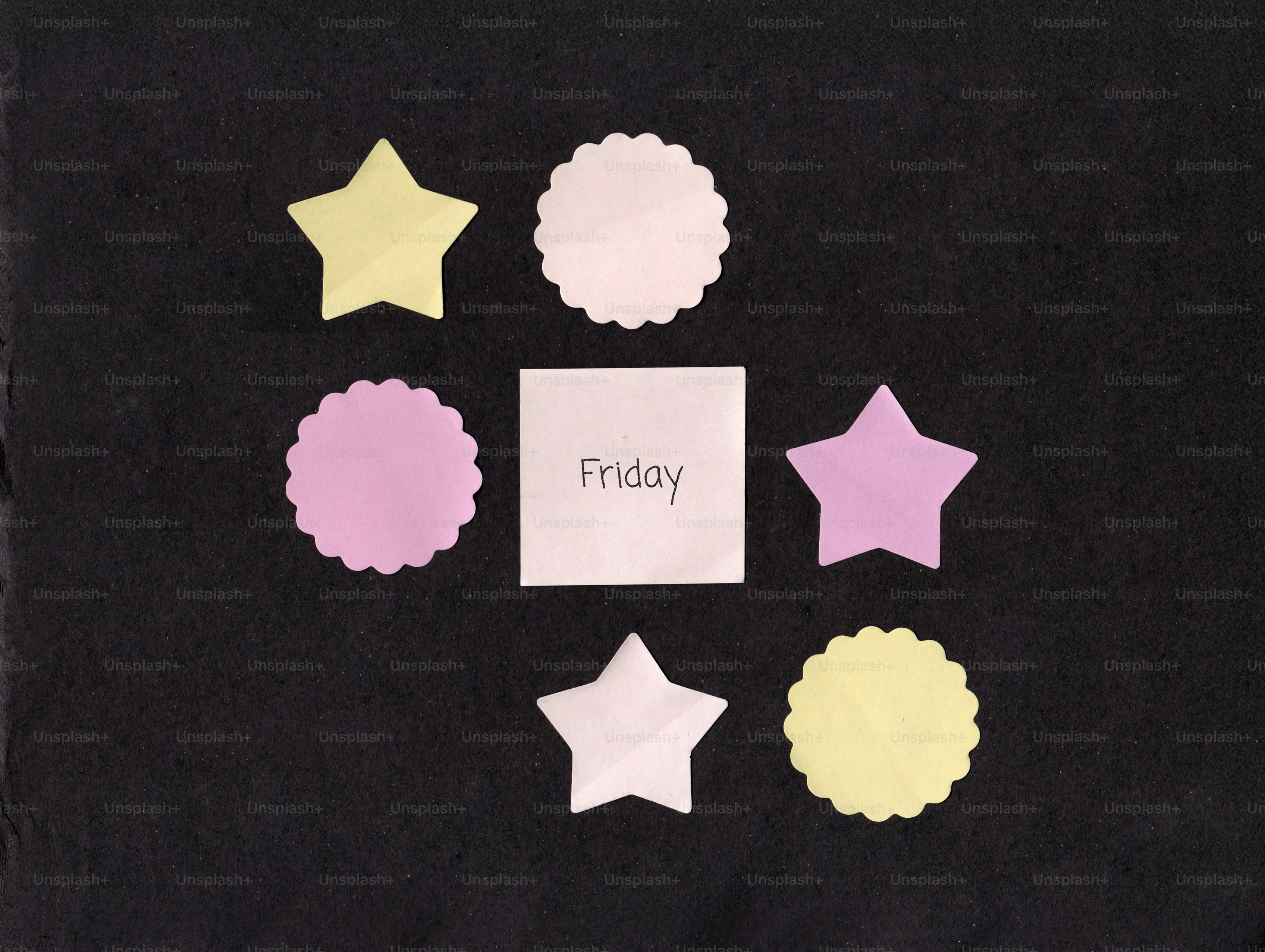 Paper shapes with 'friday' written on a dark background