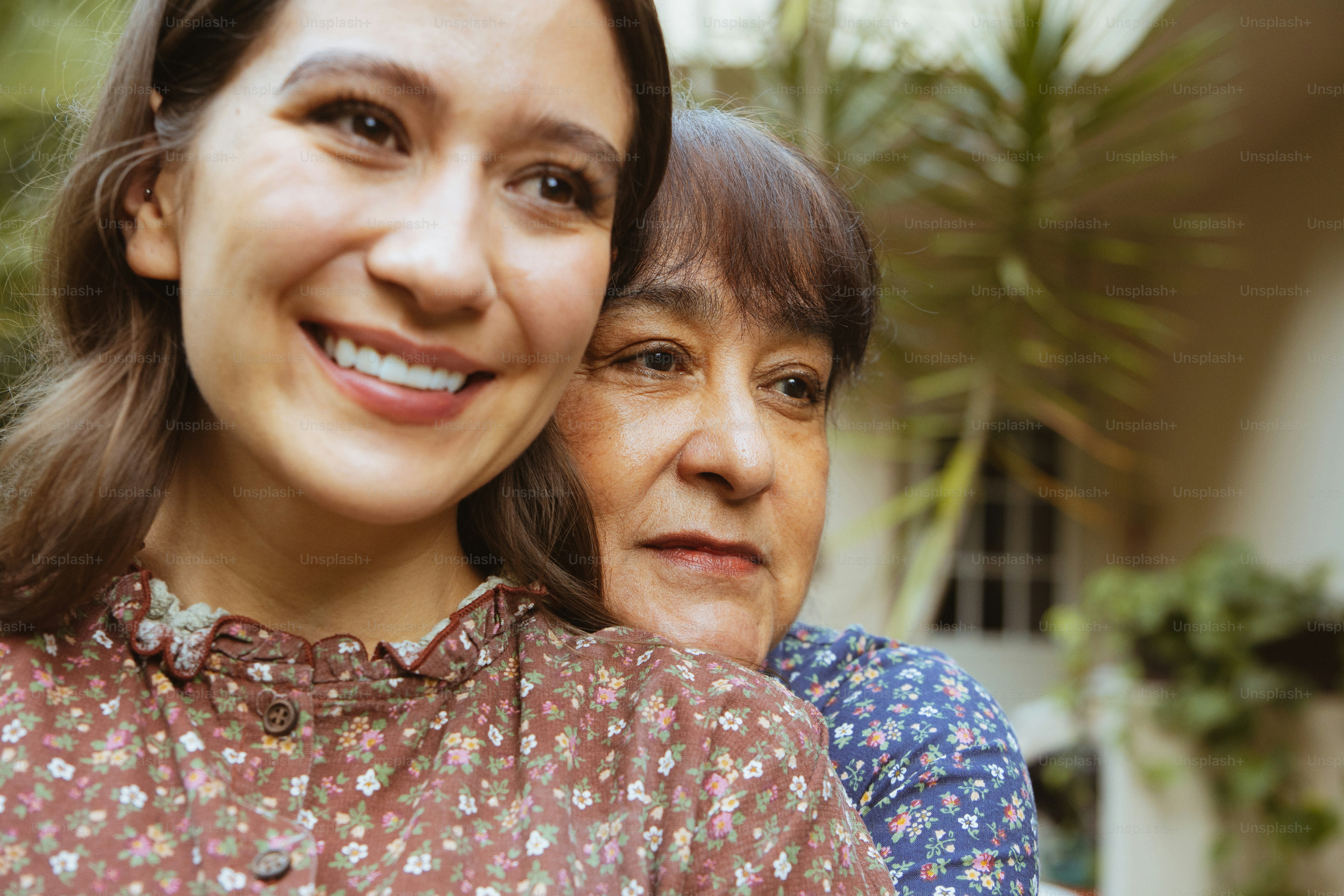 Zwei Frauen, die draußen lächeln, mit Grün im Hintergrund