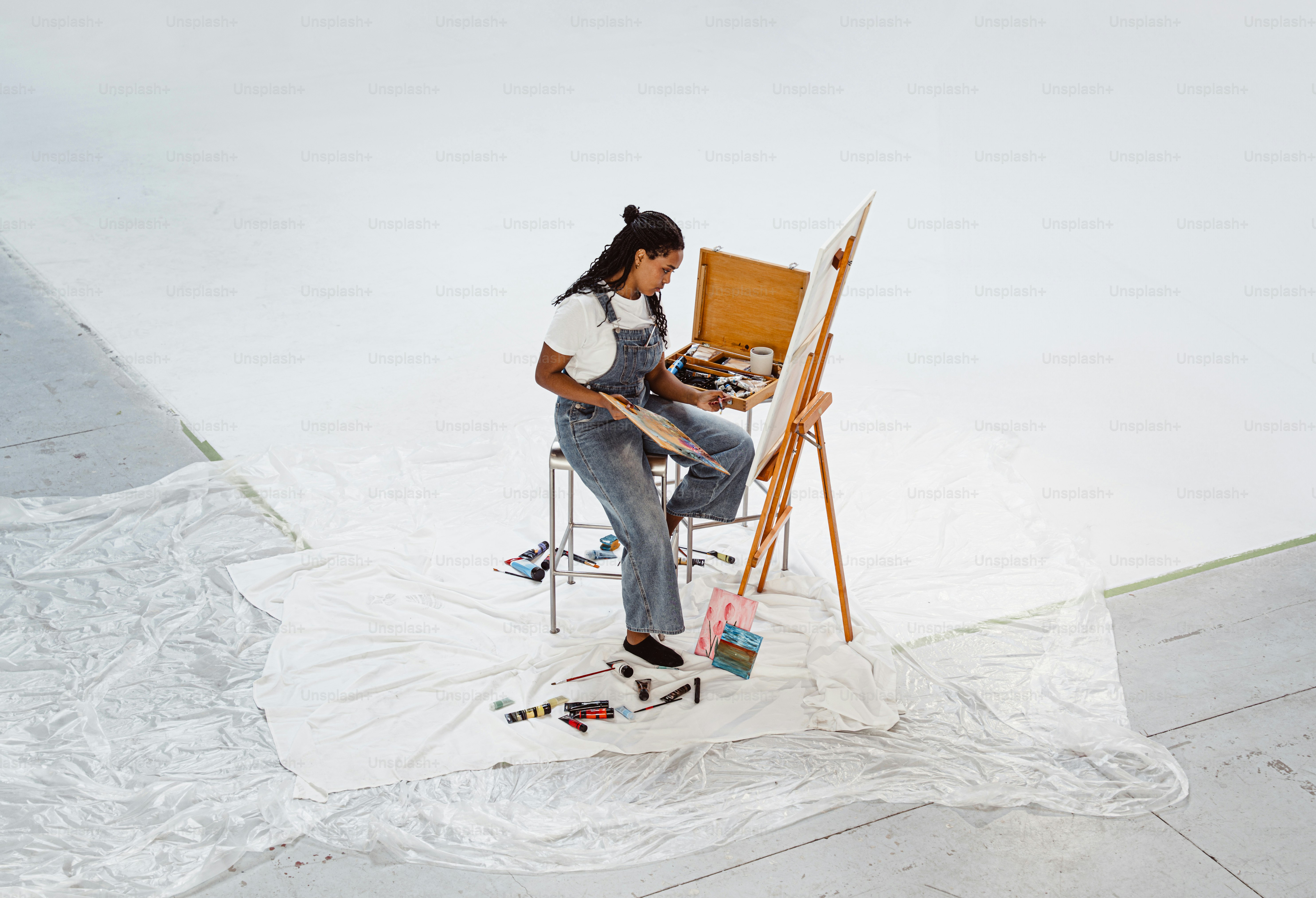 Artist painting on easel with supplies