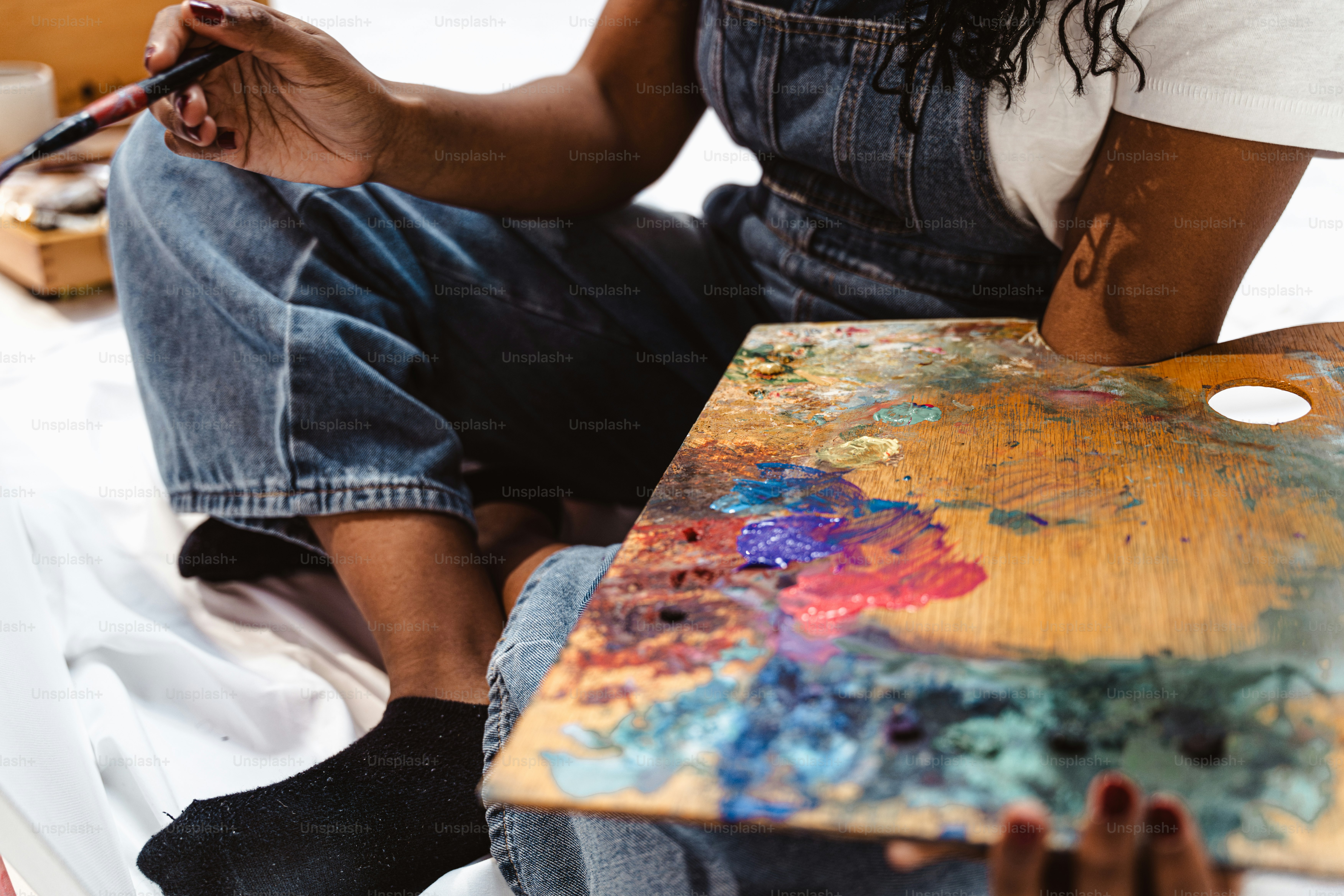 Artist mixing colorful paints on a wooden palette