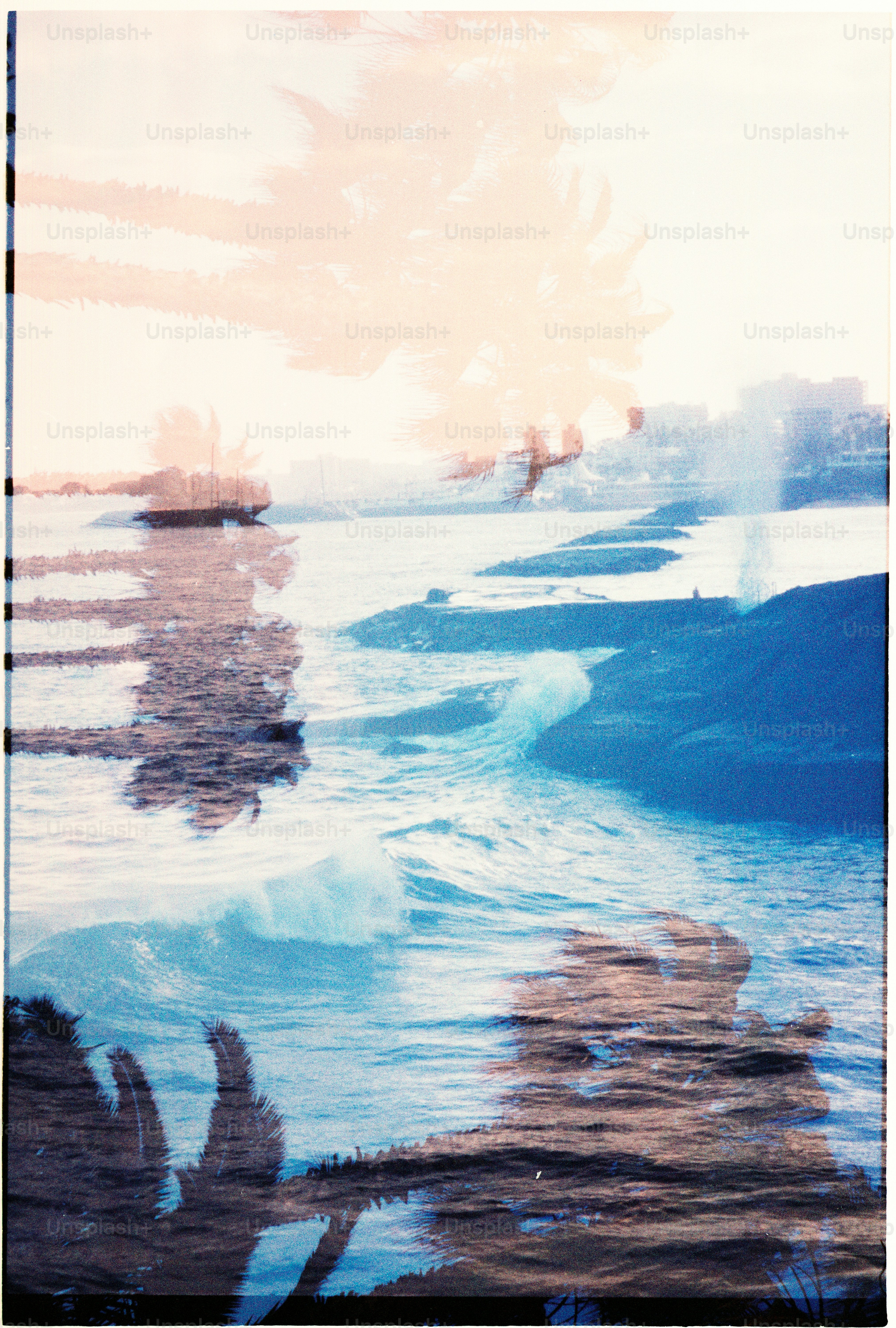 Double exposure of ocean waves and palm trees at sunset
