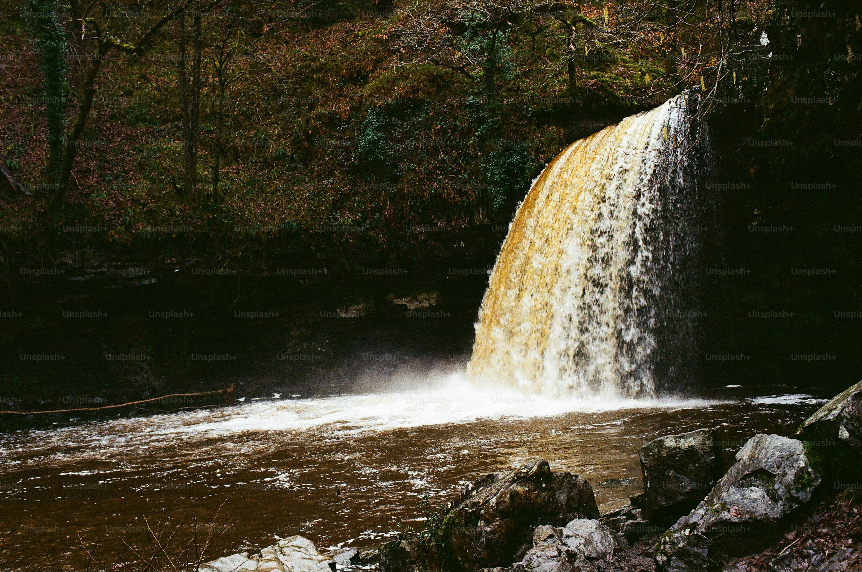 Una potente cascata sfocia in una pozza rocciosa.