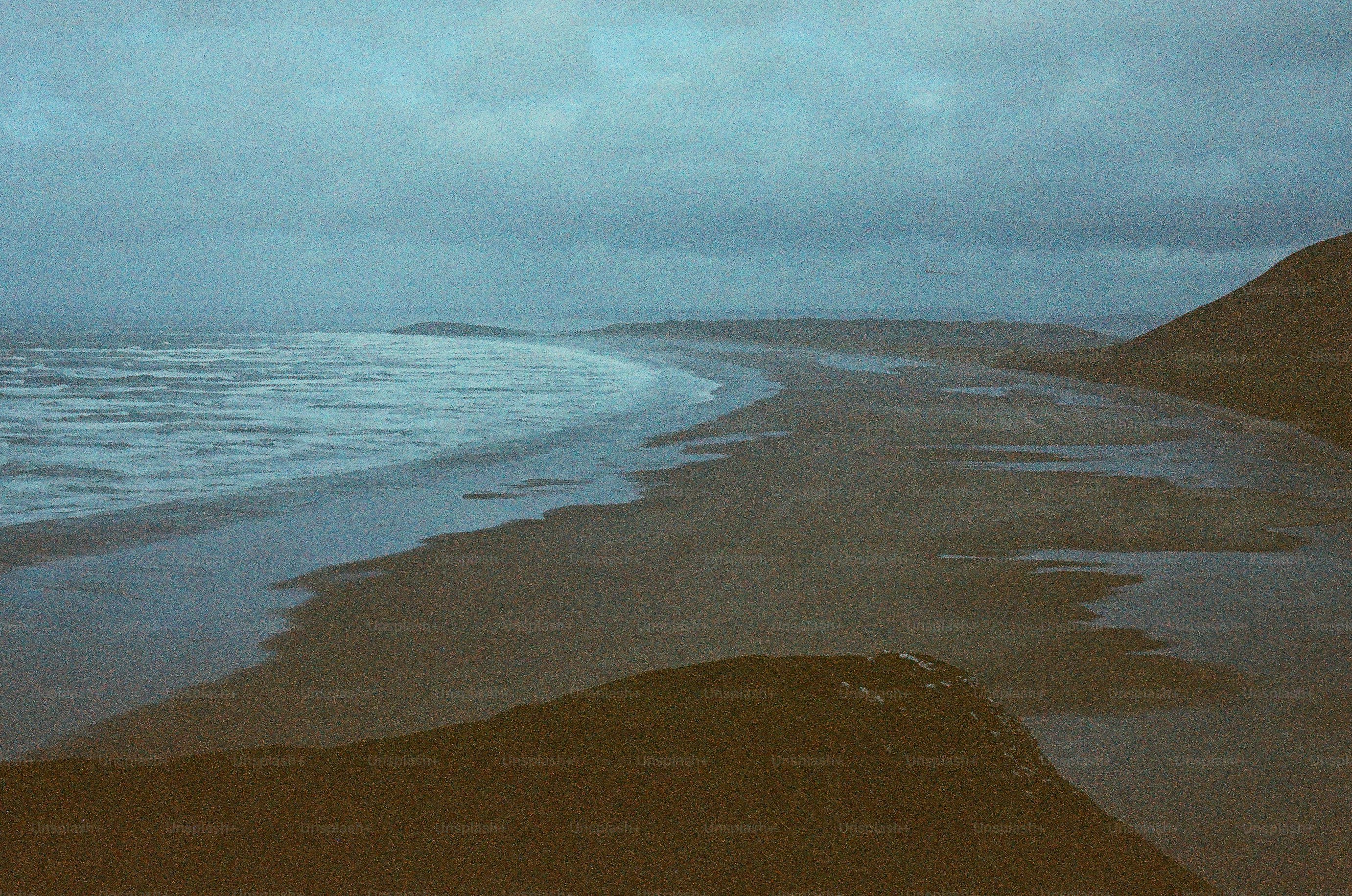 Gloomy beach with waves under a cloudy sky.
