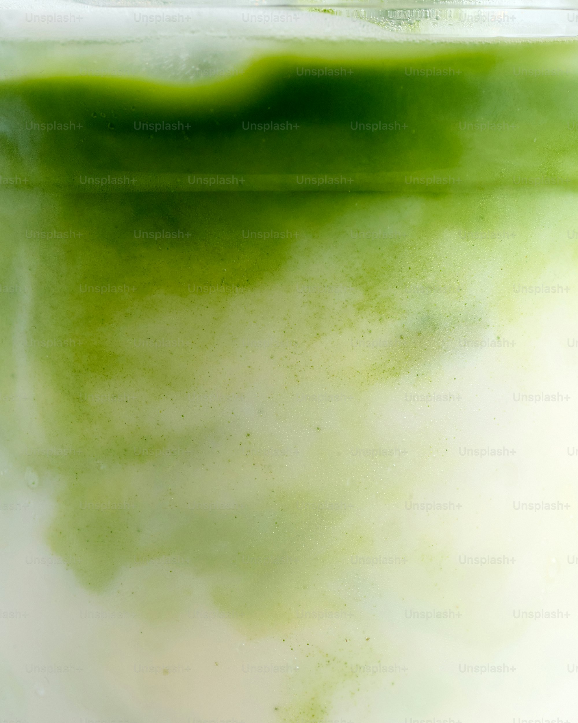 Green matcha powder swirling into milk