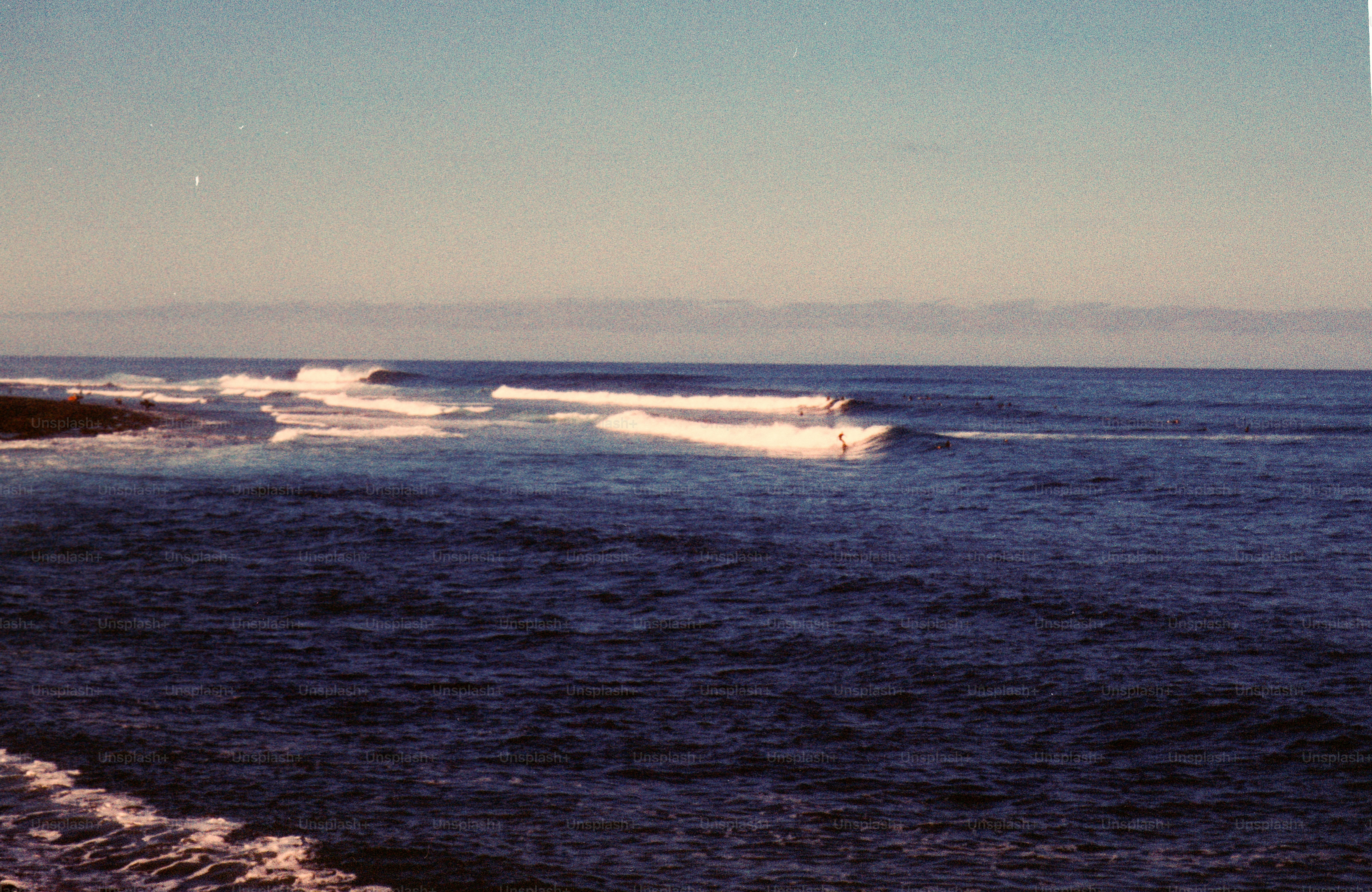 Waves breaking on a dark blue ocean under clear sky
