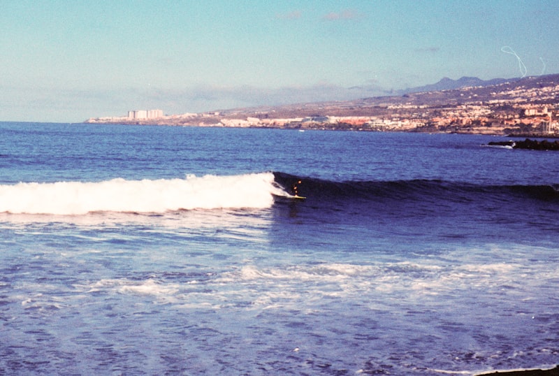 Surfista surfeando una ola cerca de un pueblo costero