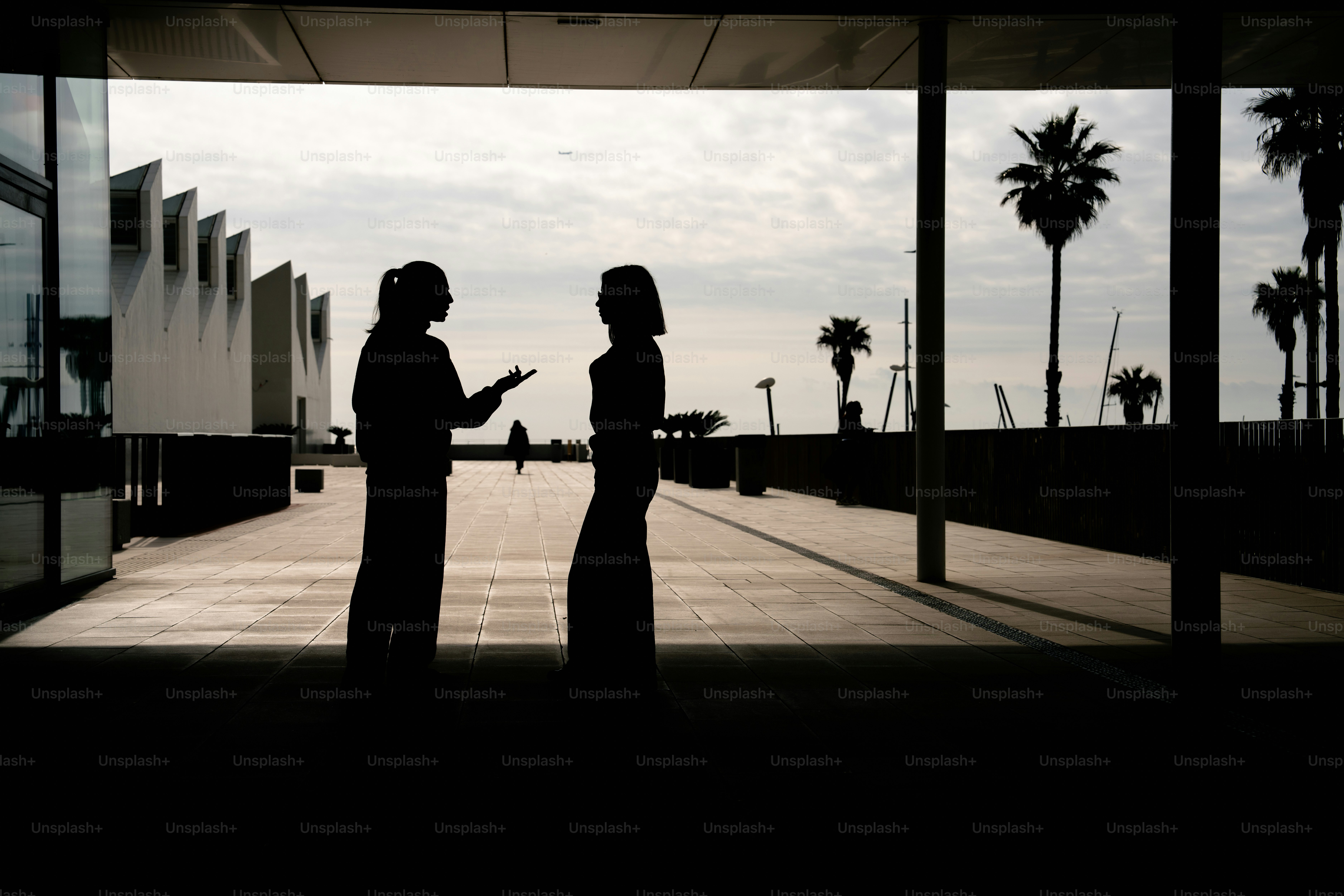 야자수를 내려다보는 발코니에서 두 사람이 대화하고 있다