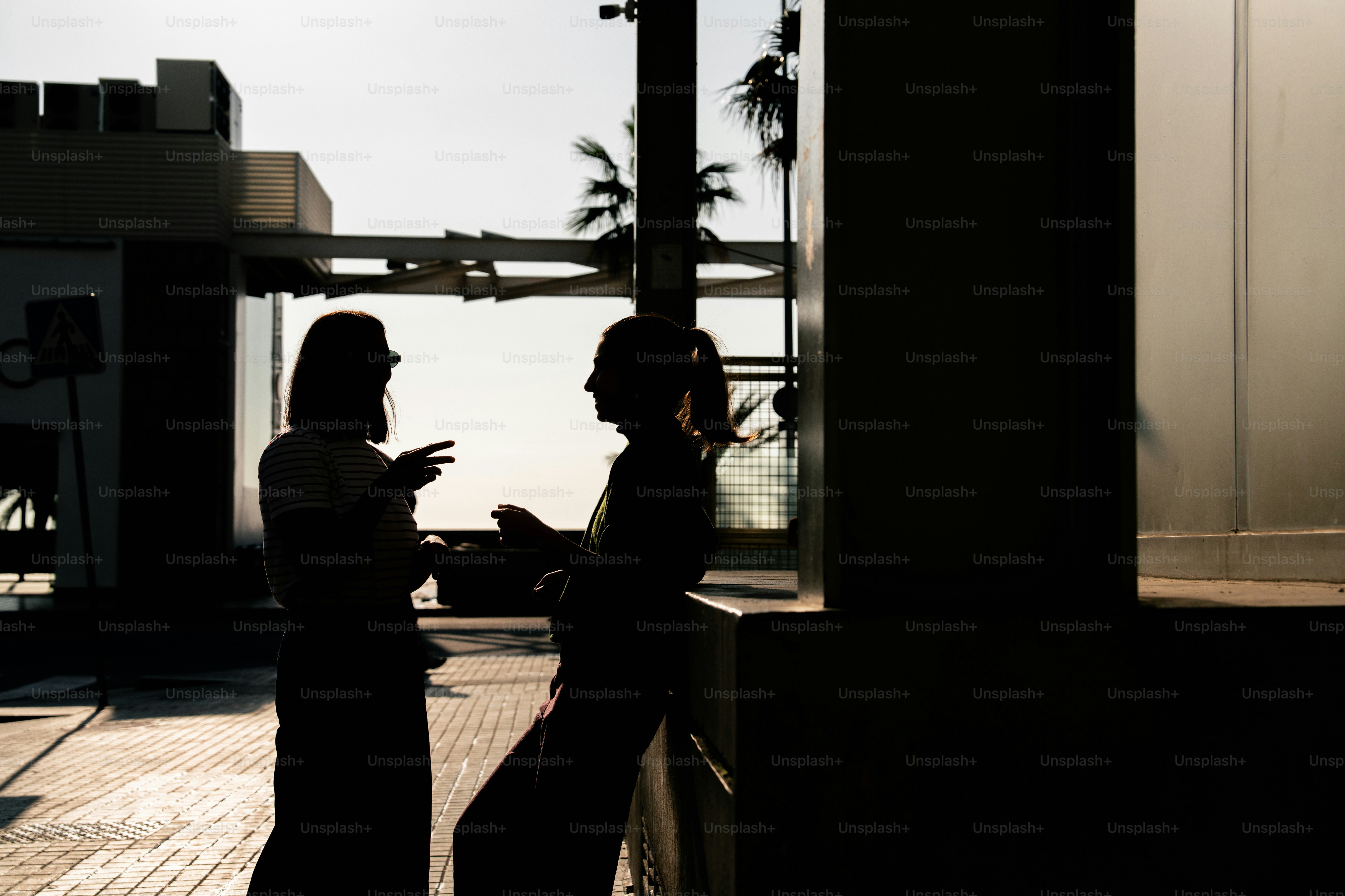 창문 근처에서 대화하는 실루엣 두 사람이 있다