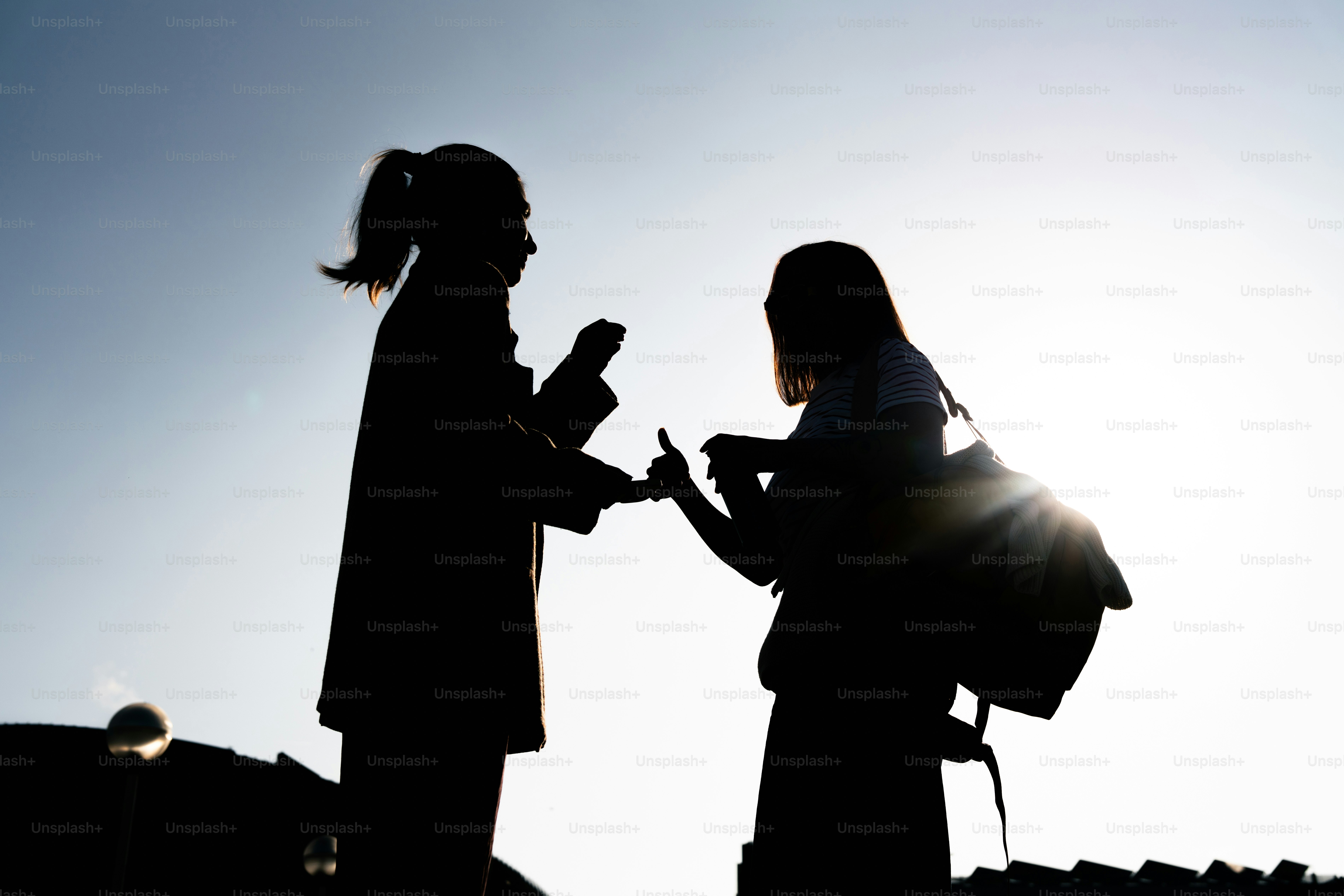 밝은 하늘을 배경으로 실루엣으로 드리운 두 사람의 실루엣
