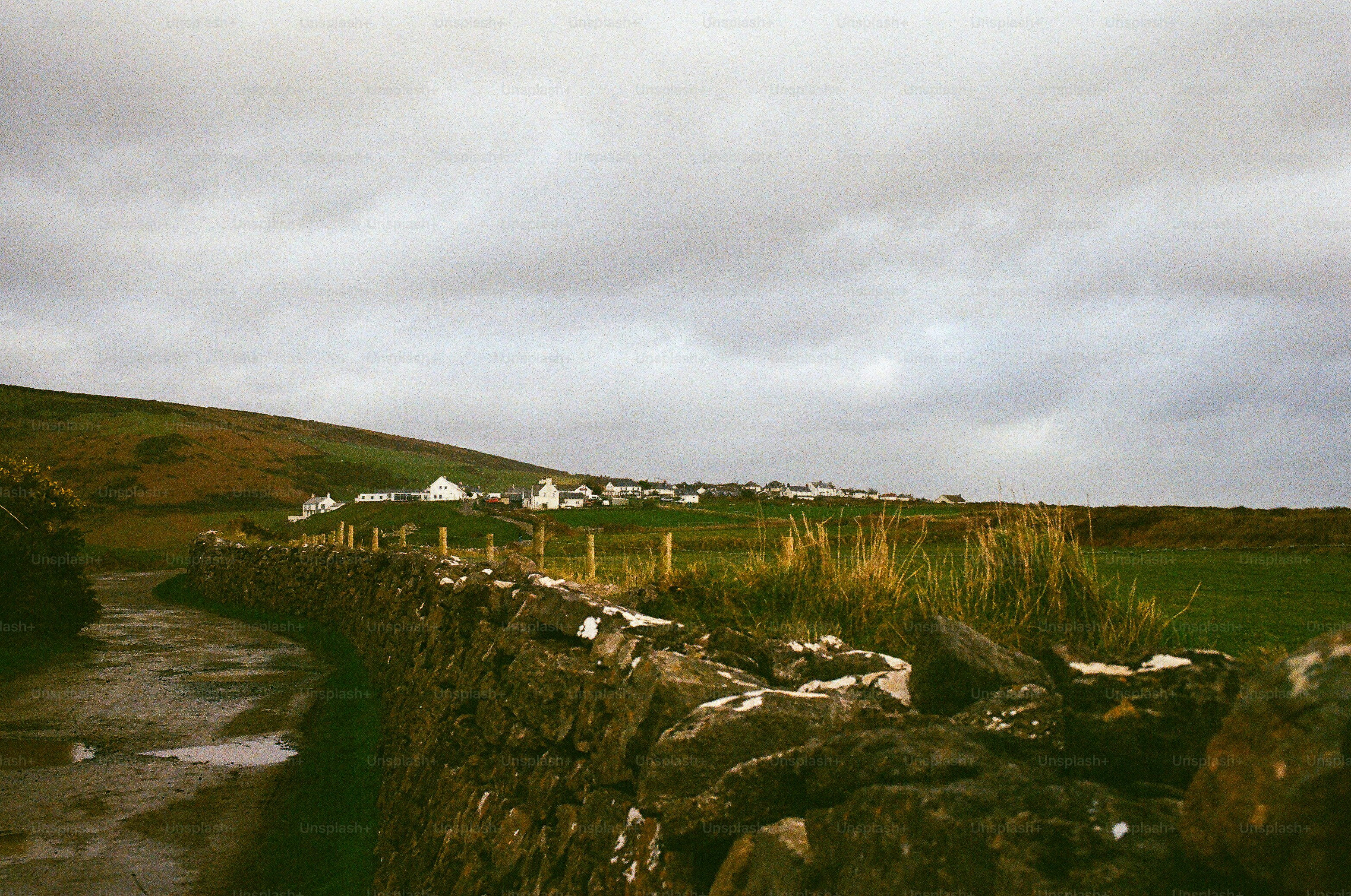 Stone wall leads to houses on a cloudy day.
