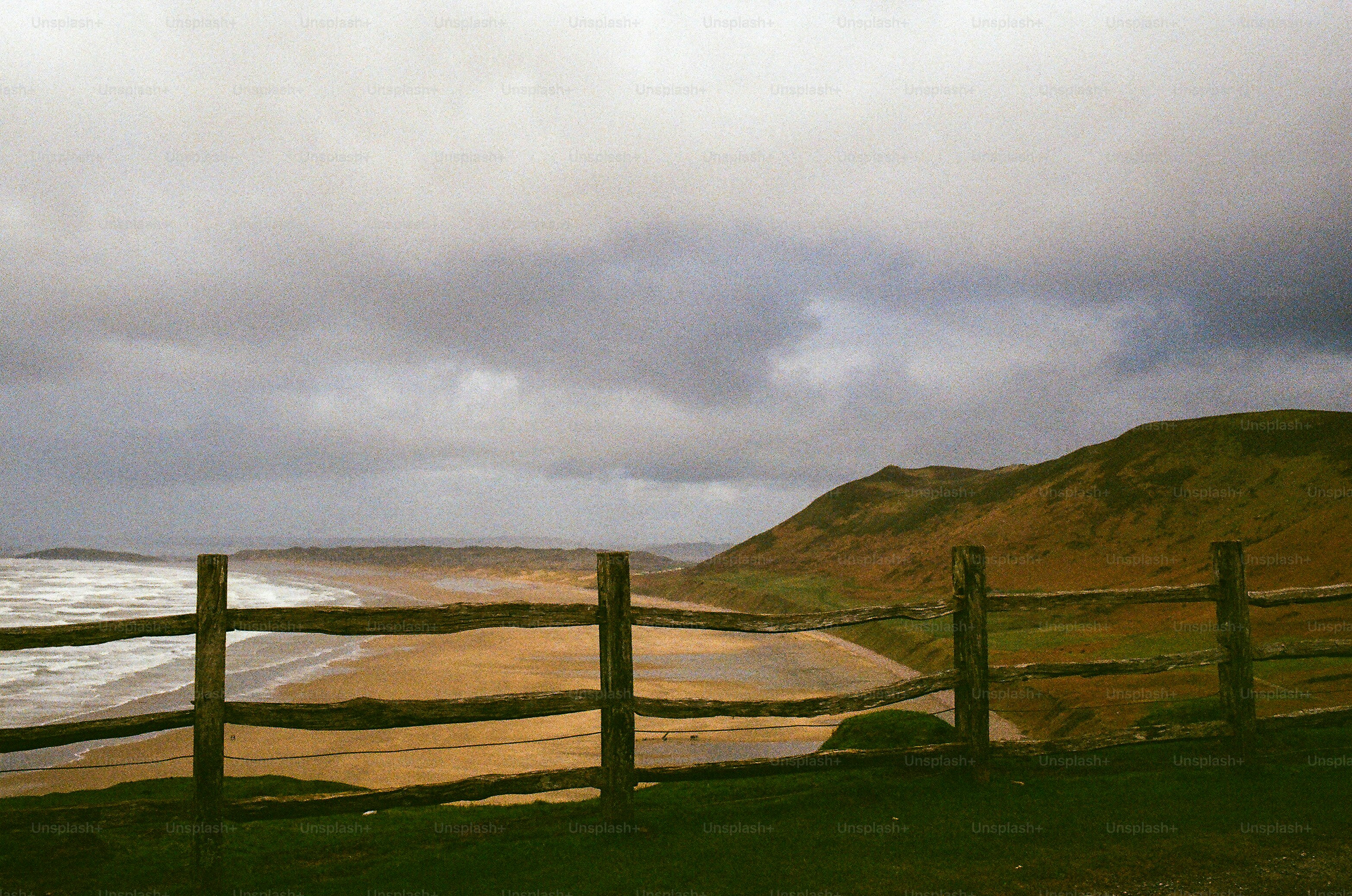Wooden fence overlooks a sandy beach and ocean waves. photo – Beach ...