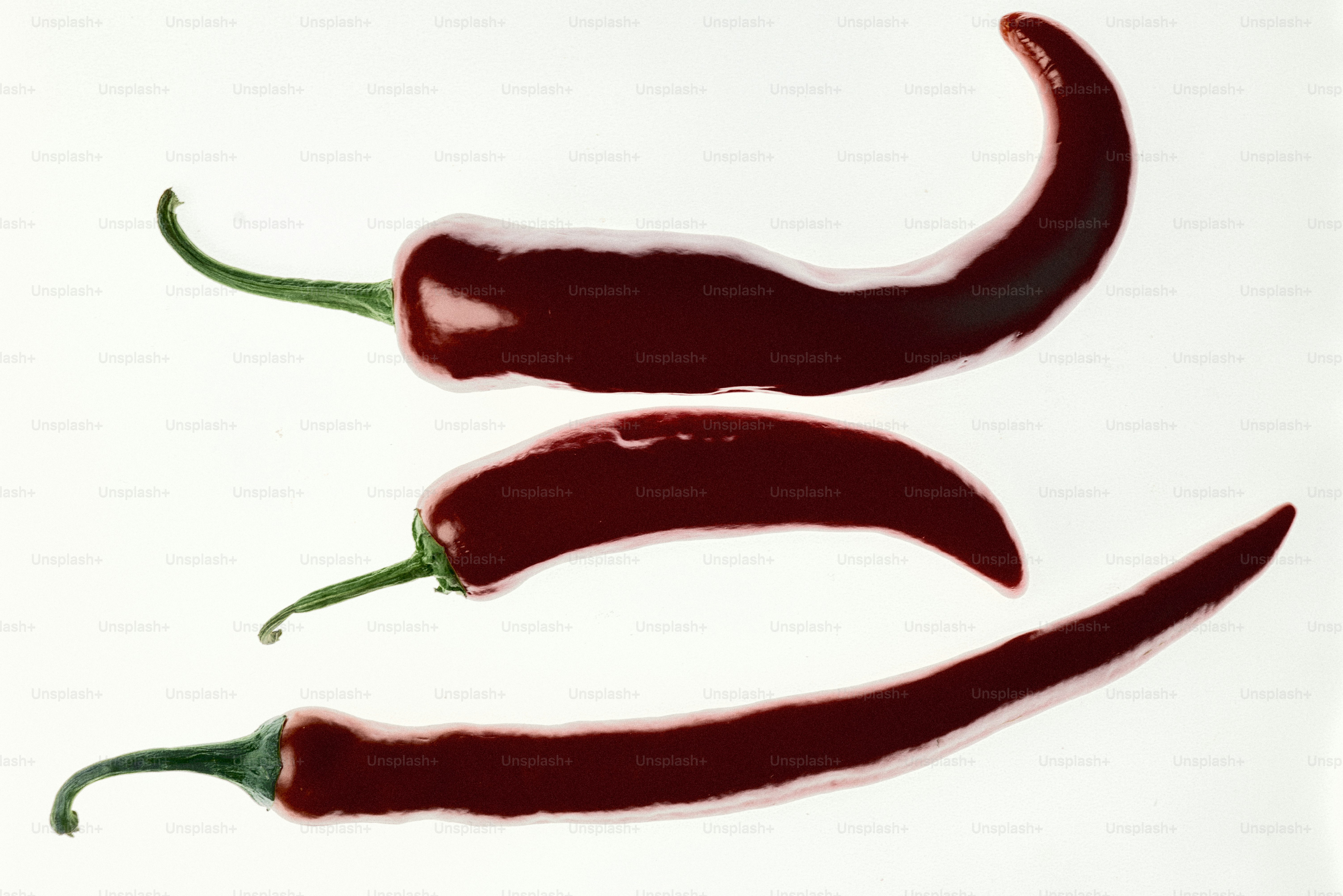 Tres chiles rojo oscuro sobre fondo blanco