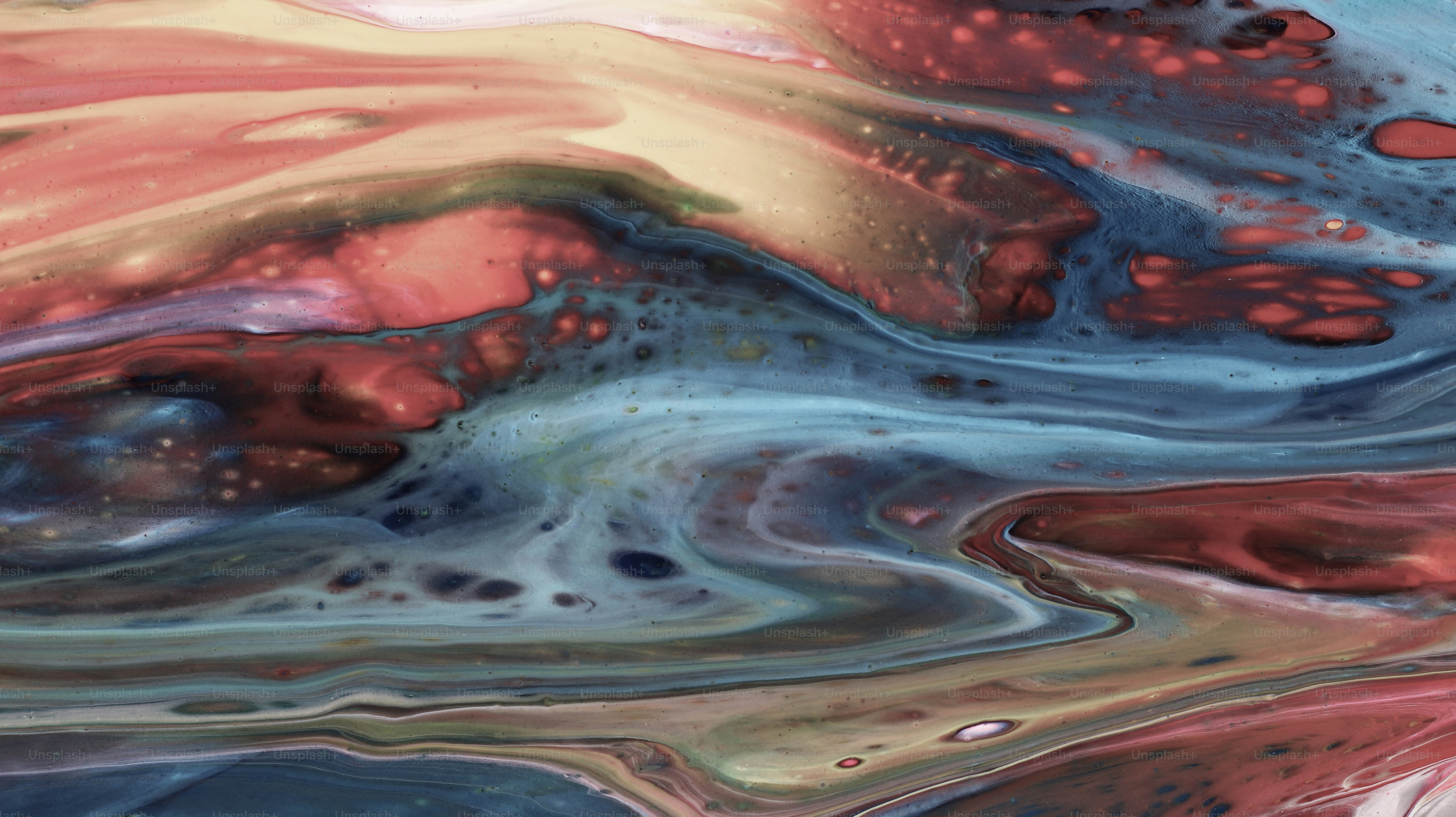 Vortici astratti di vernice rossa, blu e gialla.