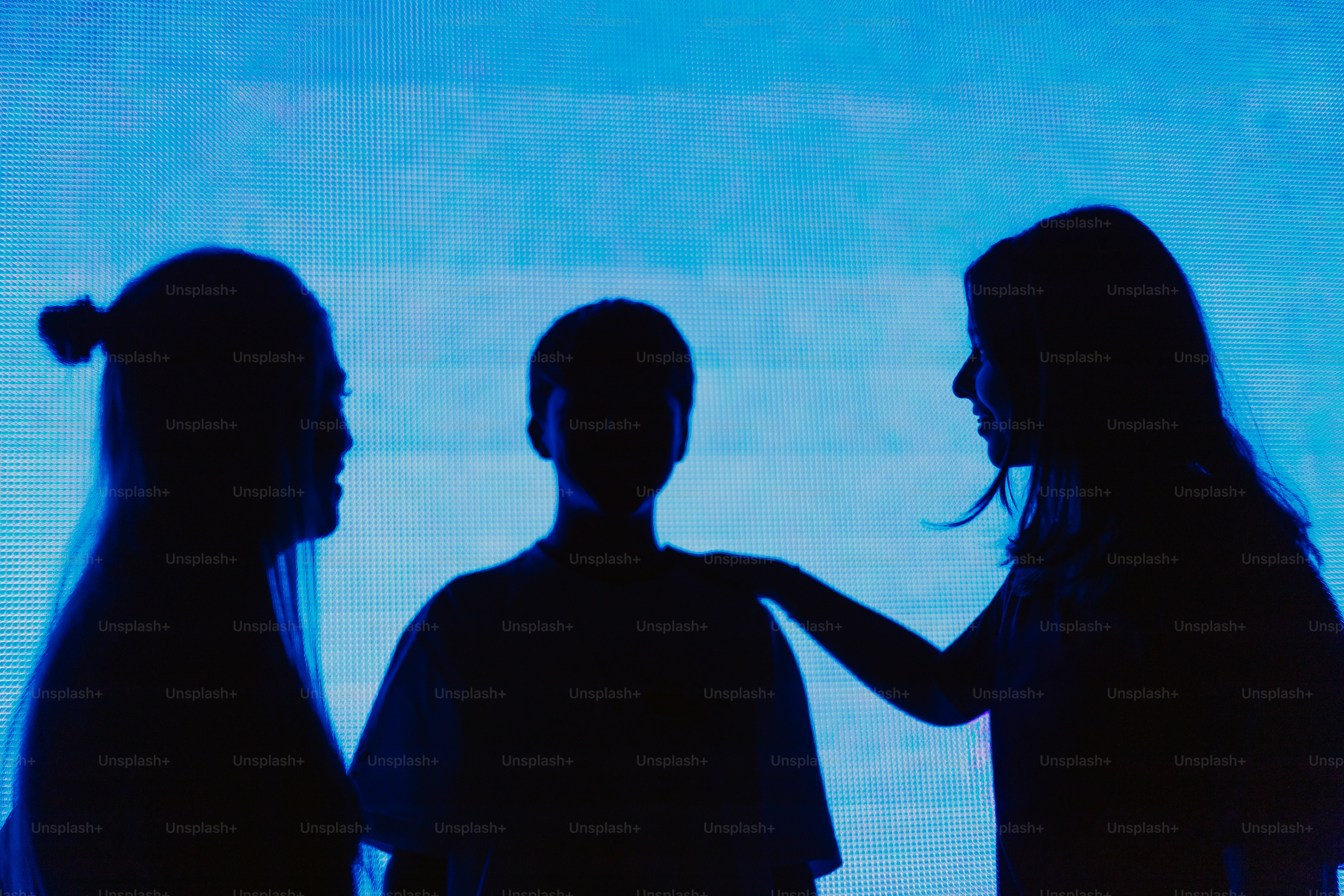 Silhouettes of three people against a blue background.