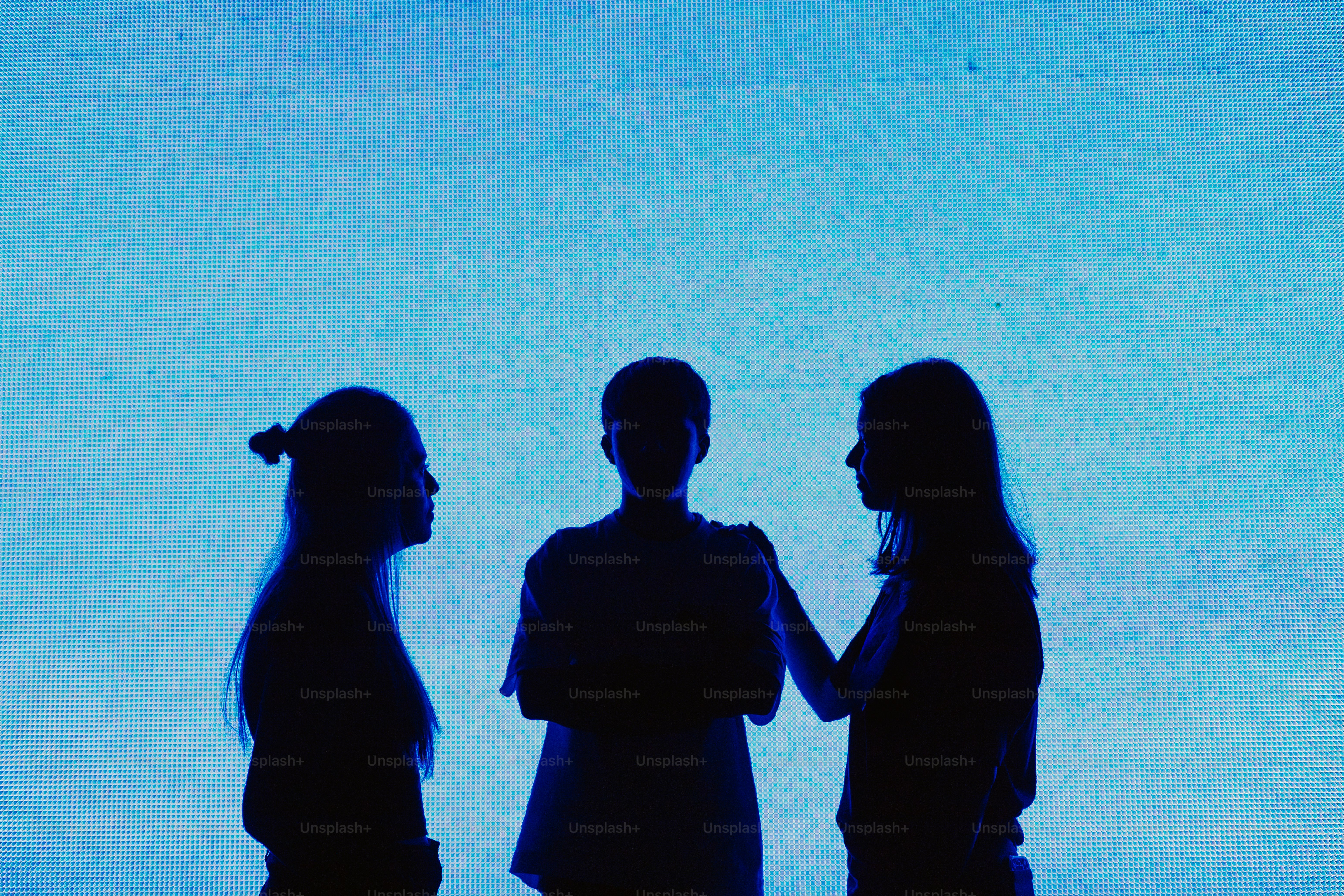 Three people silhouetted against a blue background