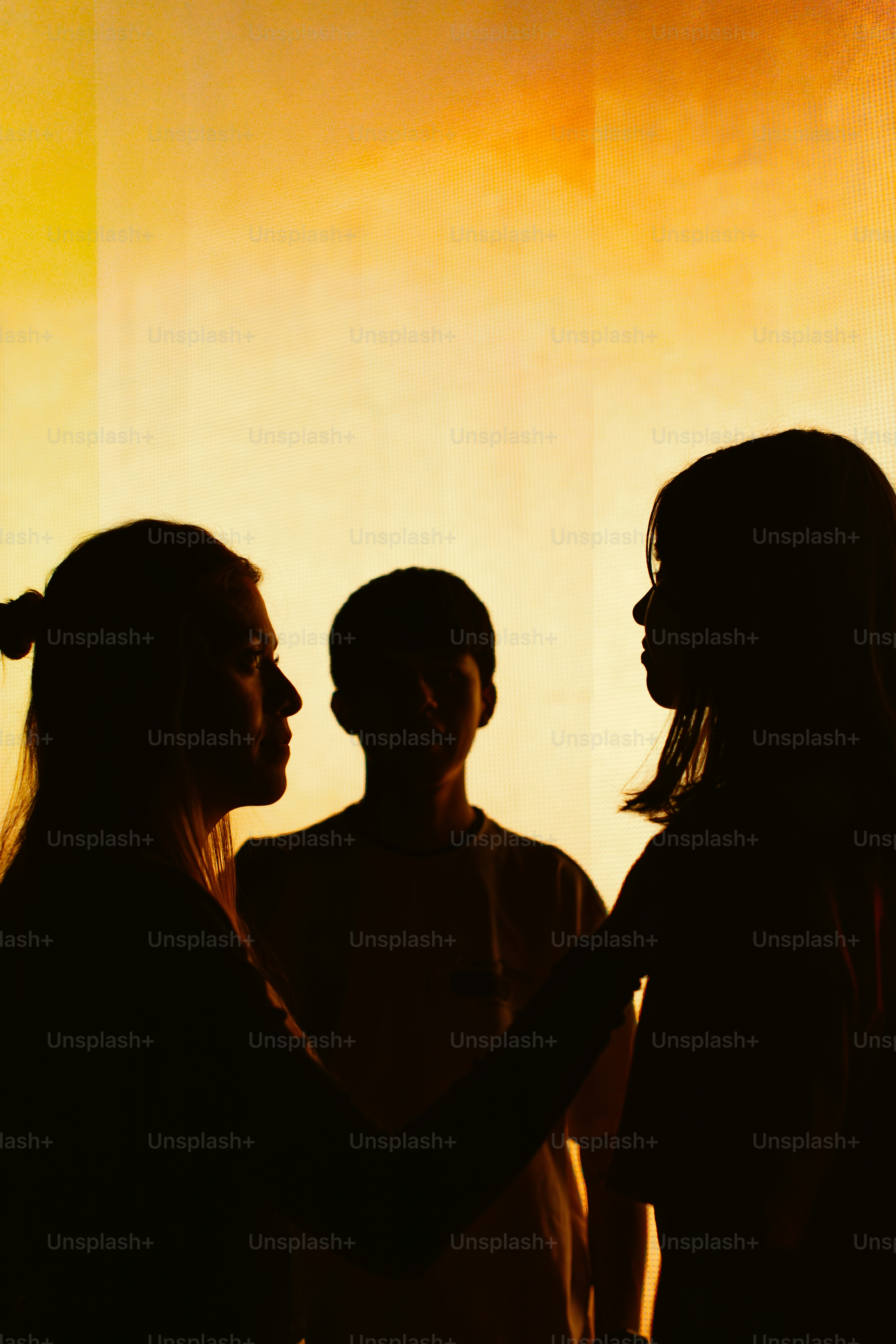 Silhouettes of three people against a warm background.