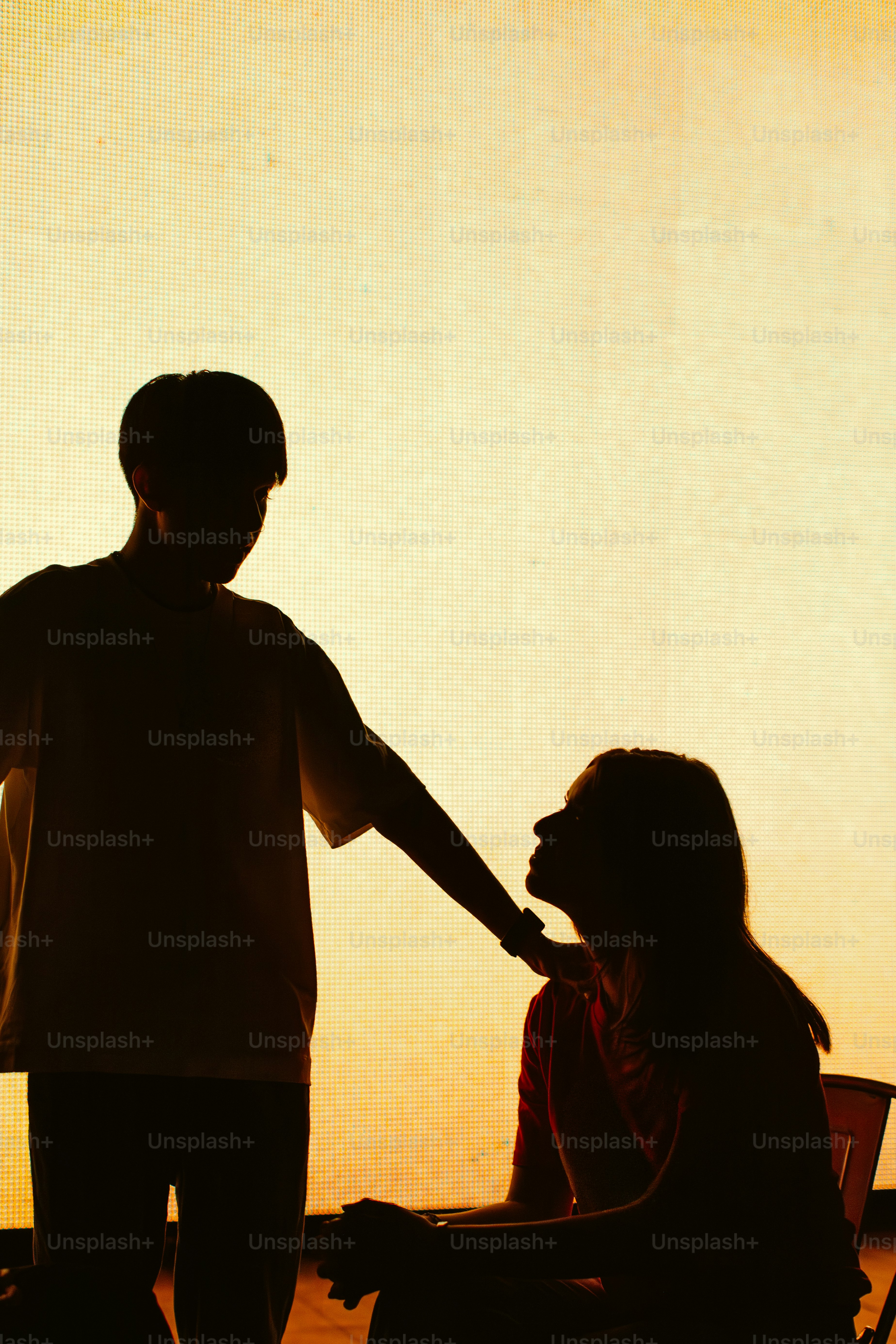 Silhouettes of a couple against a warm sunset sky