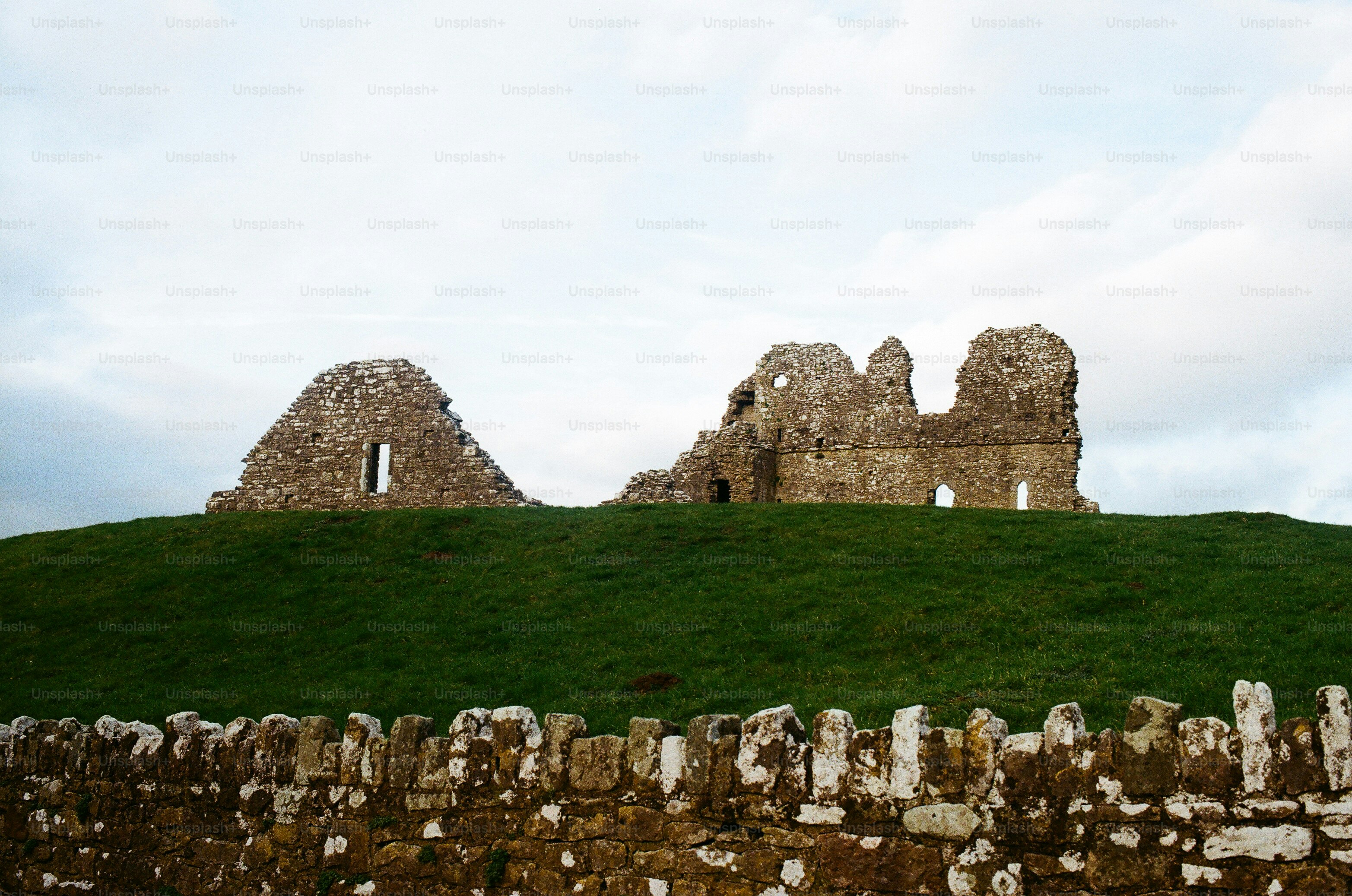 Rovine antiche di un castello in cima a una collina erbosa