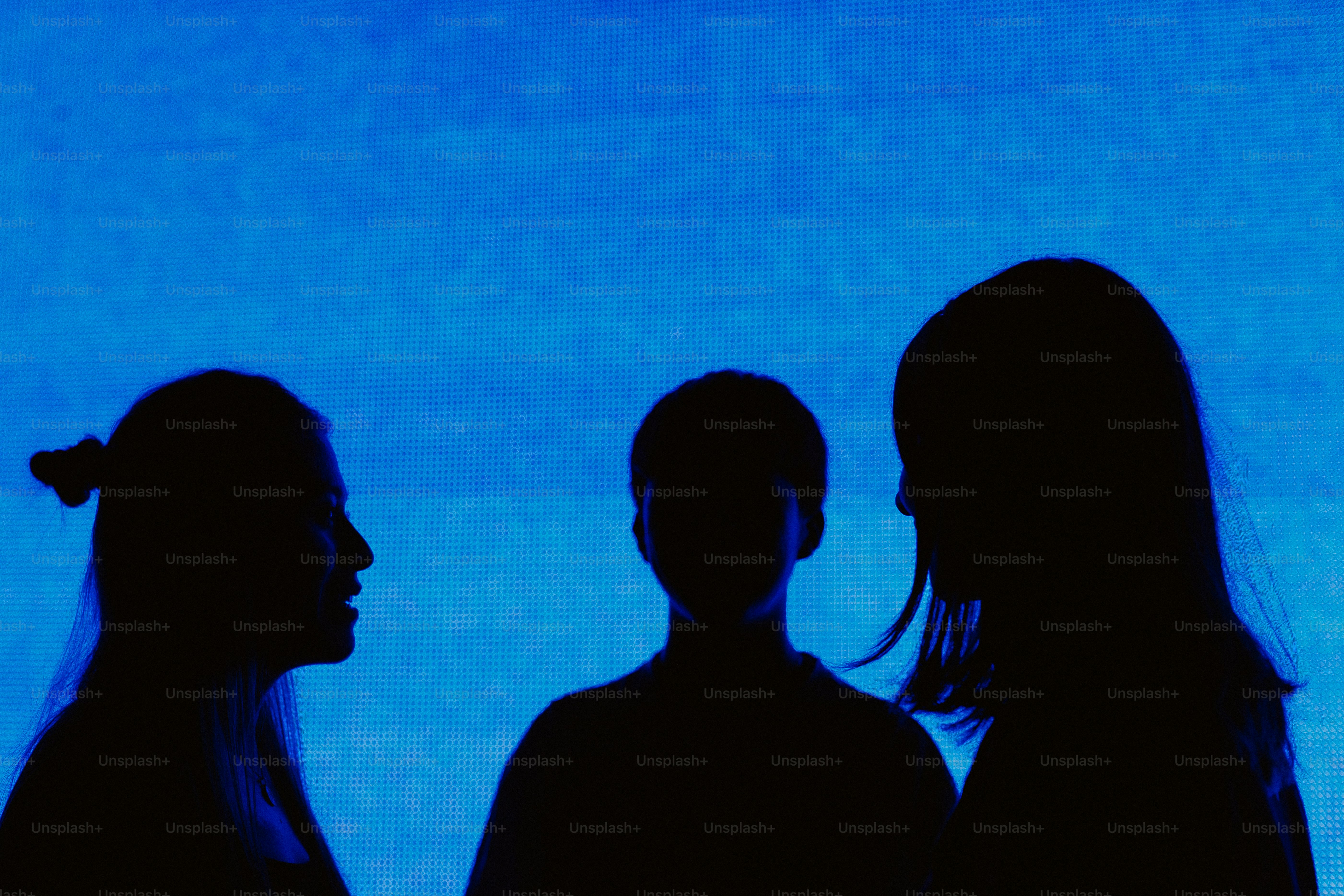 Silhouettes of three people against a blue background