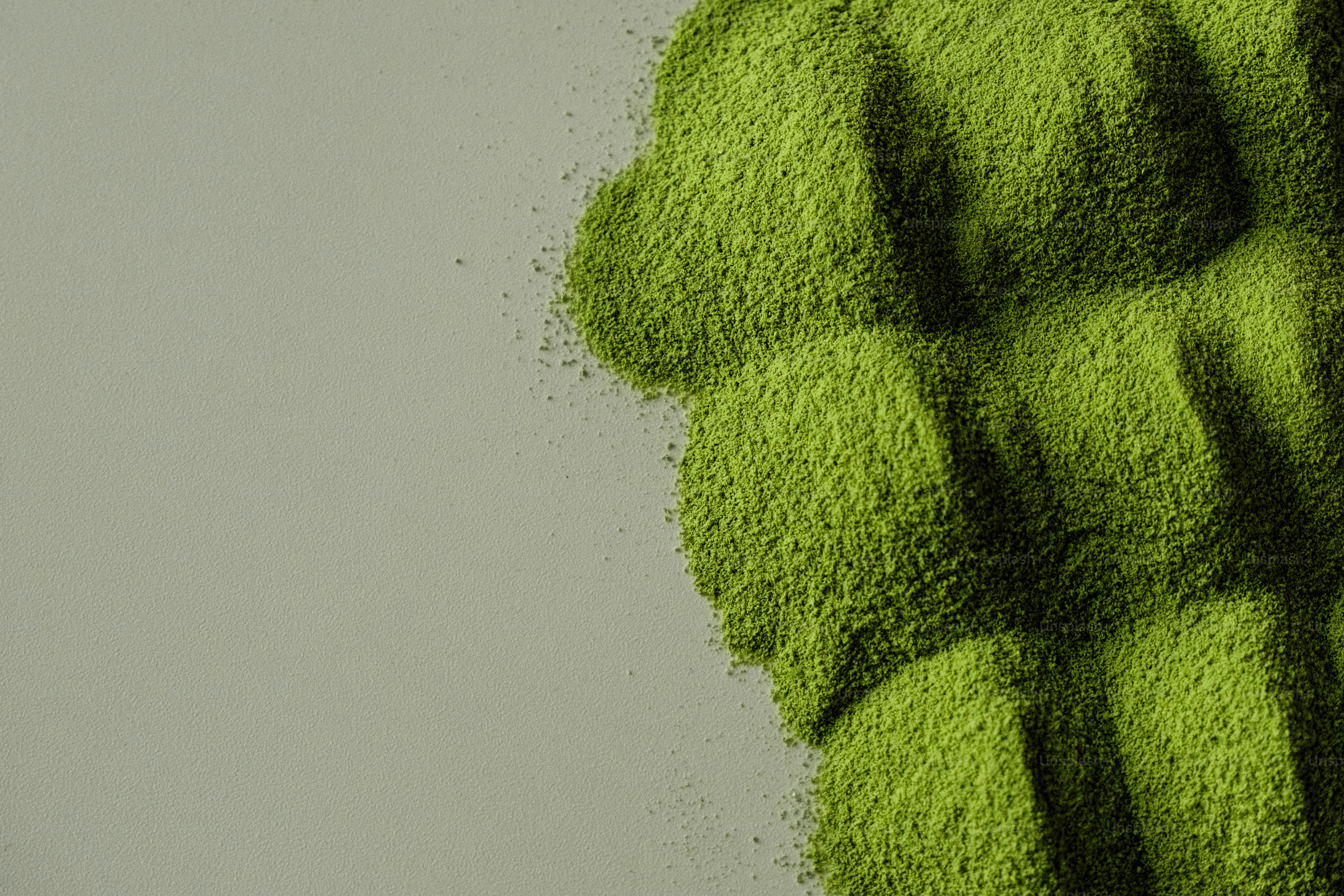 Pile of bright green matcha powder on a gray surface