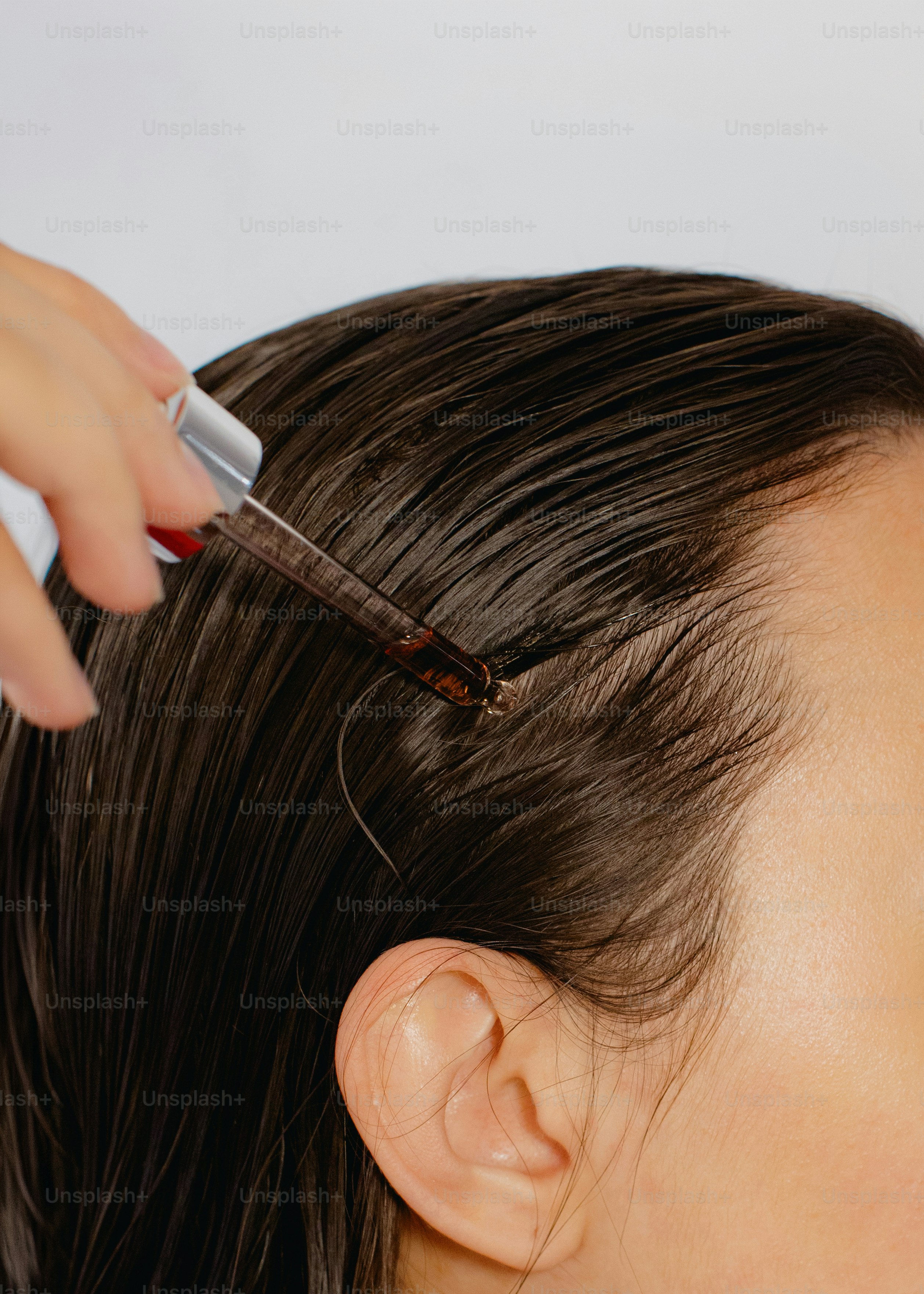 Applying serum to wet hair with a dropper.