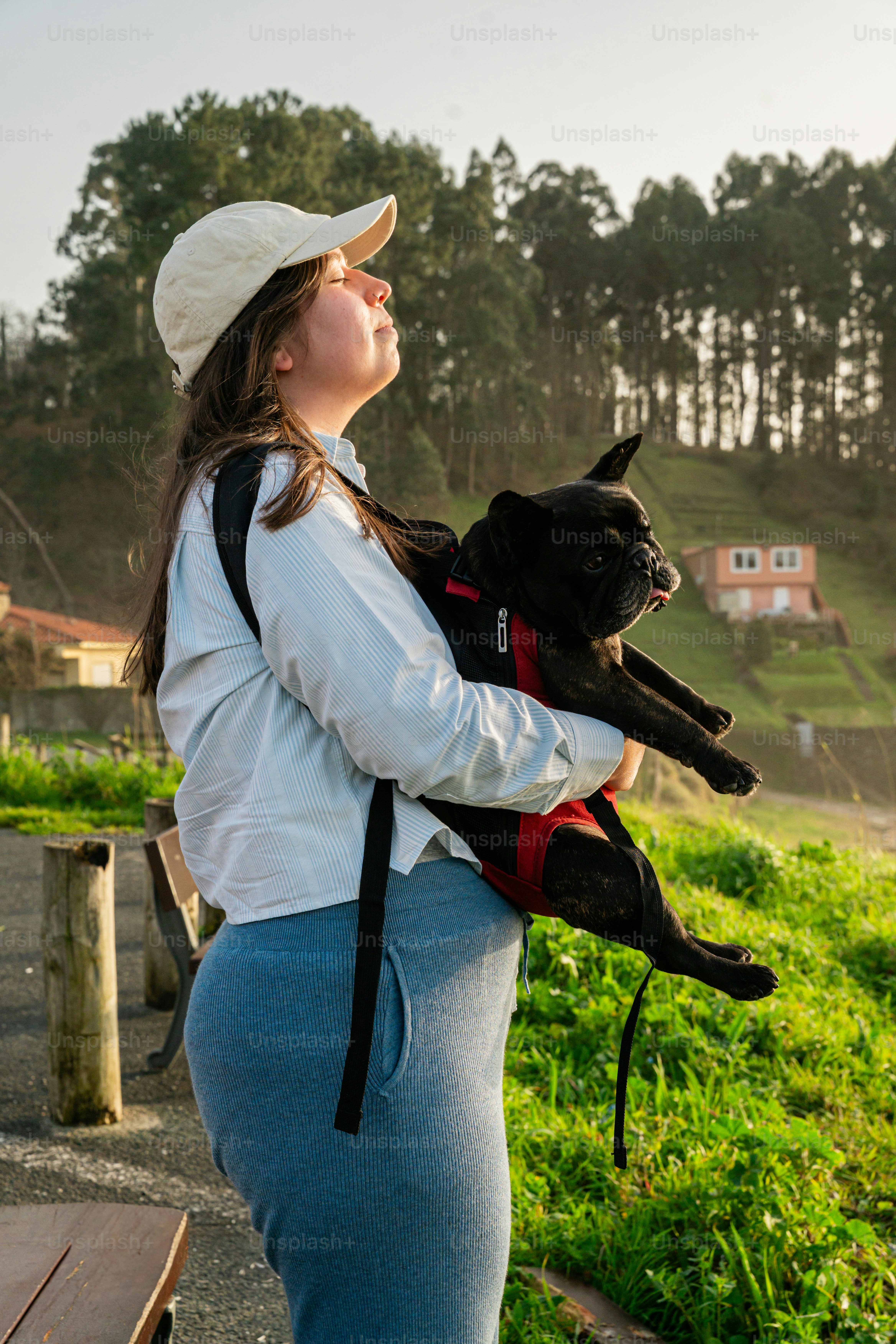 Woman holding a black french bulldog outdoors