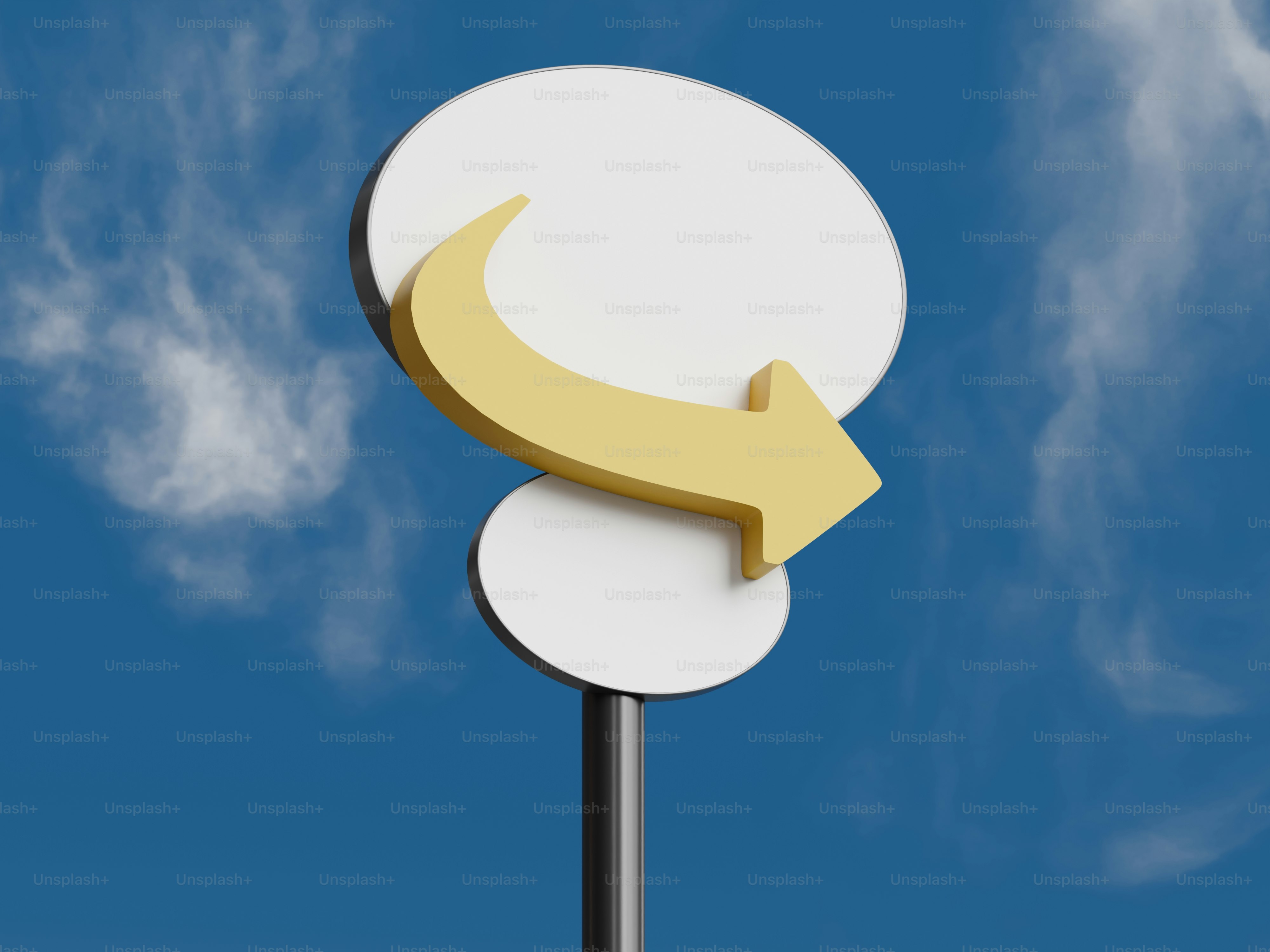 하늘을 배경으로 노란 화살표가 그려진 흰색 원형 표지판