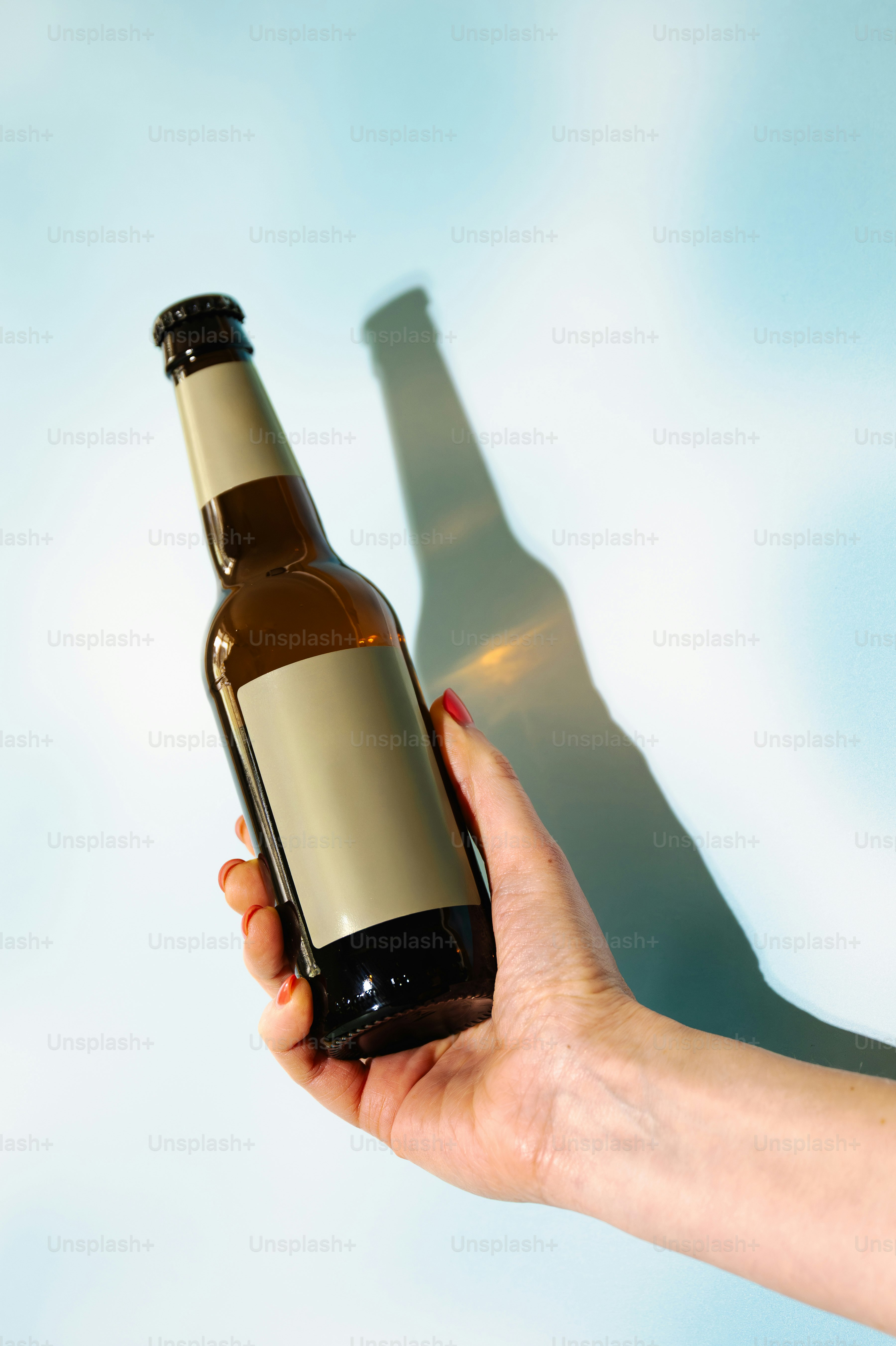 Tenant une bouteille en verre marron avec une étiquette vierge.