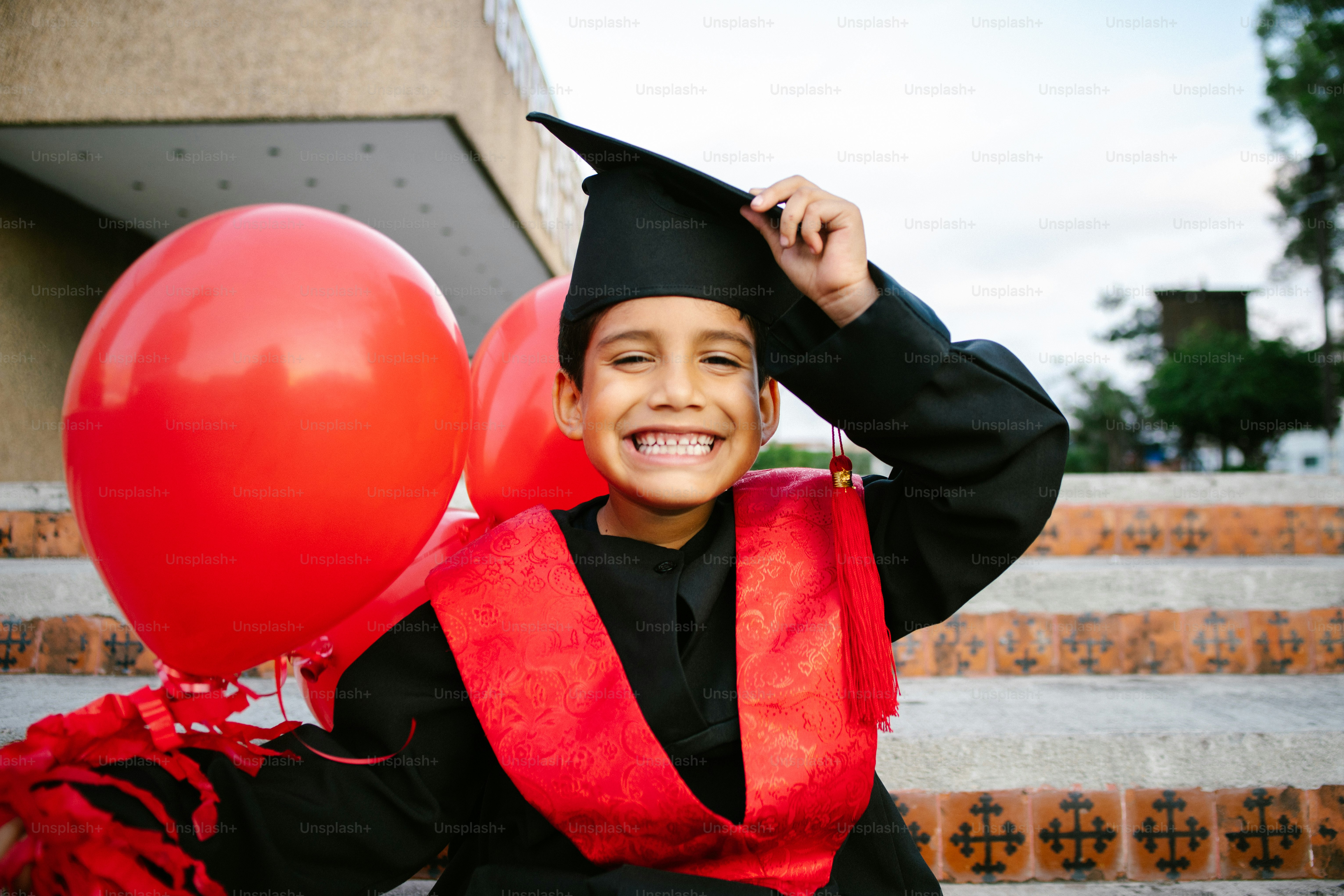 Smiling boy in graduation cap and gown with balloons photo – Education ...