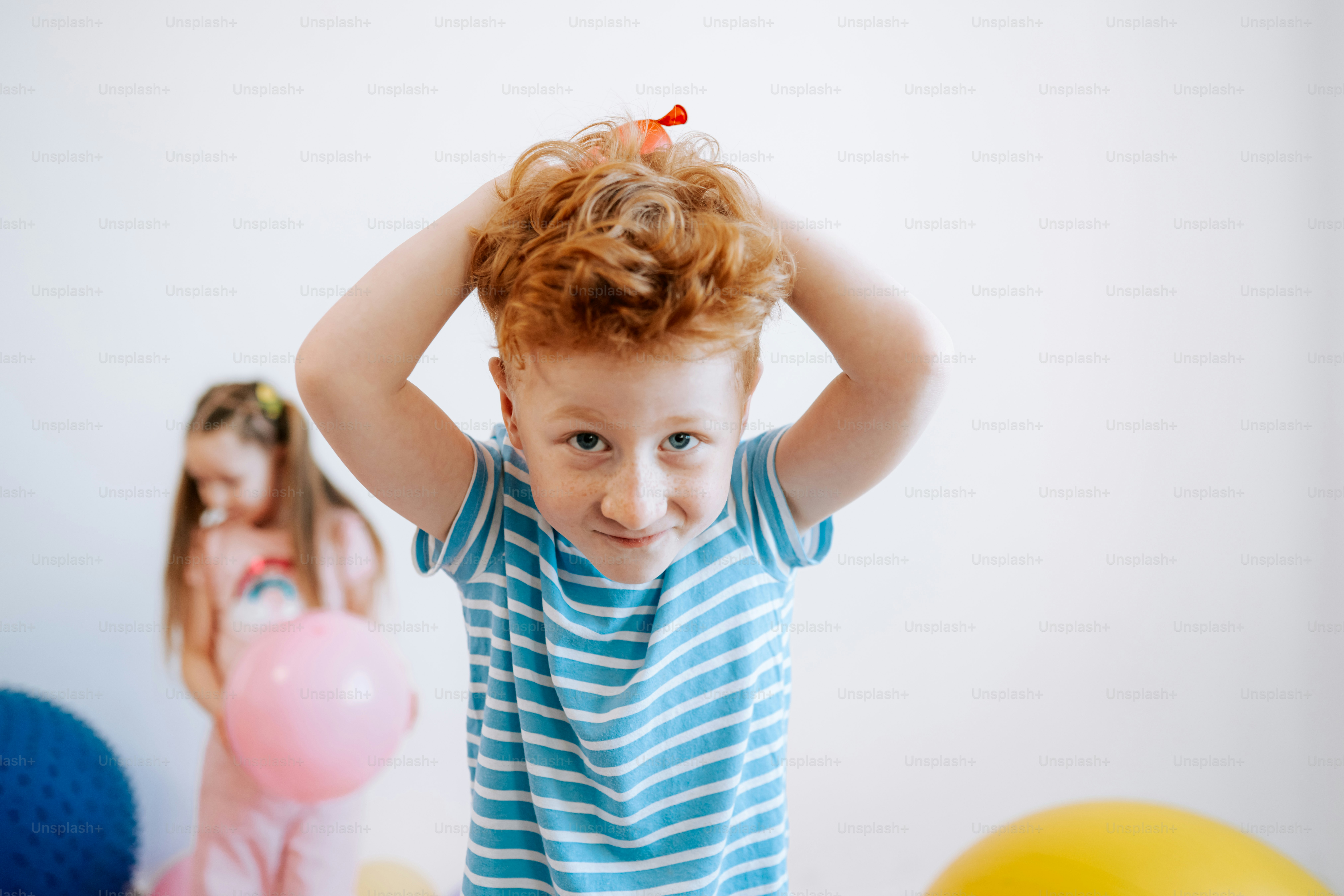 Young boy with red hair plays with balloons