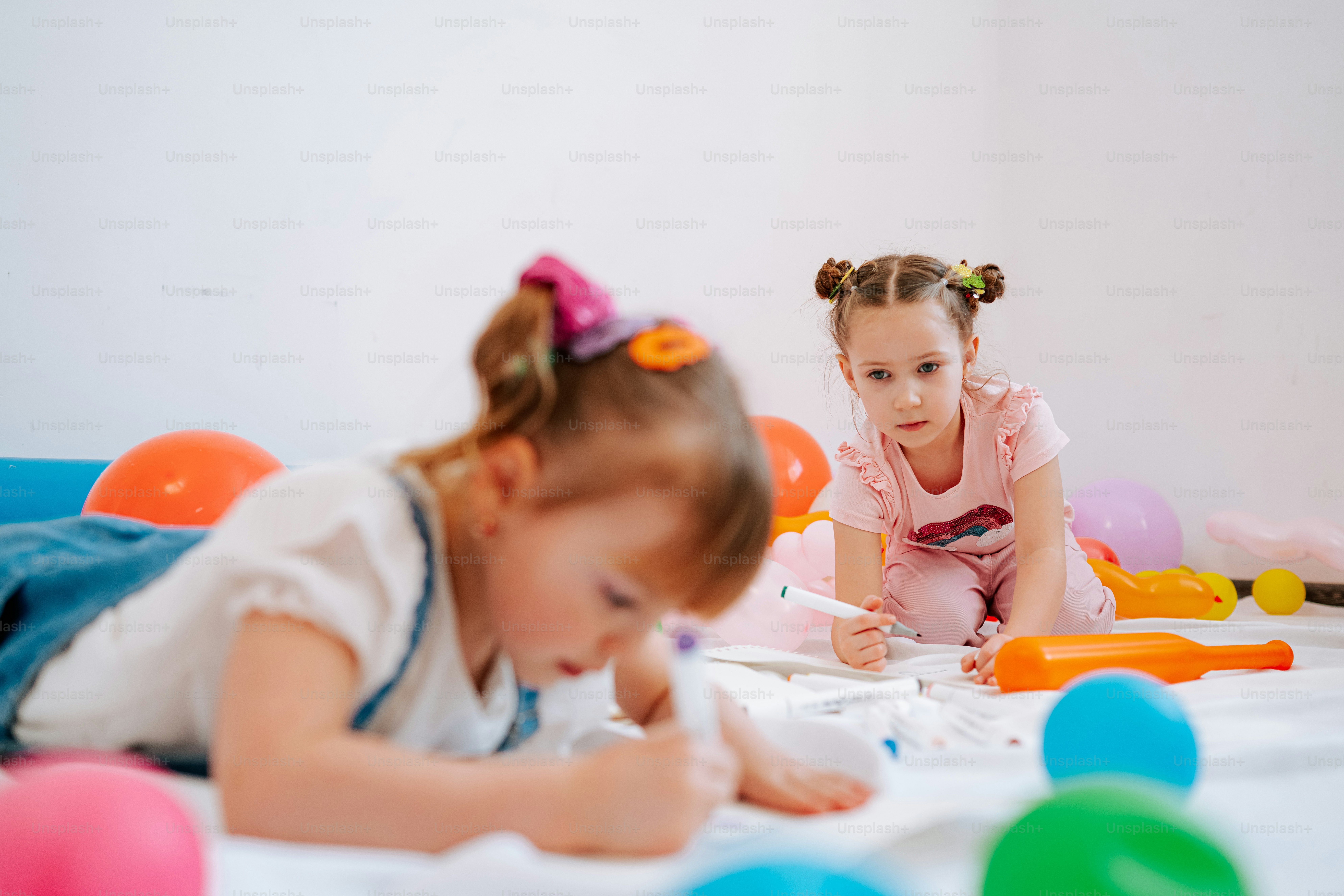 Two young girls playing with toys on the floor.