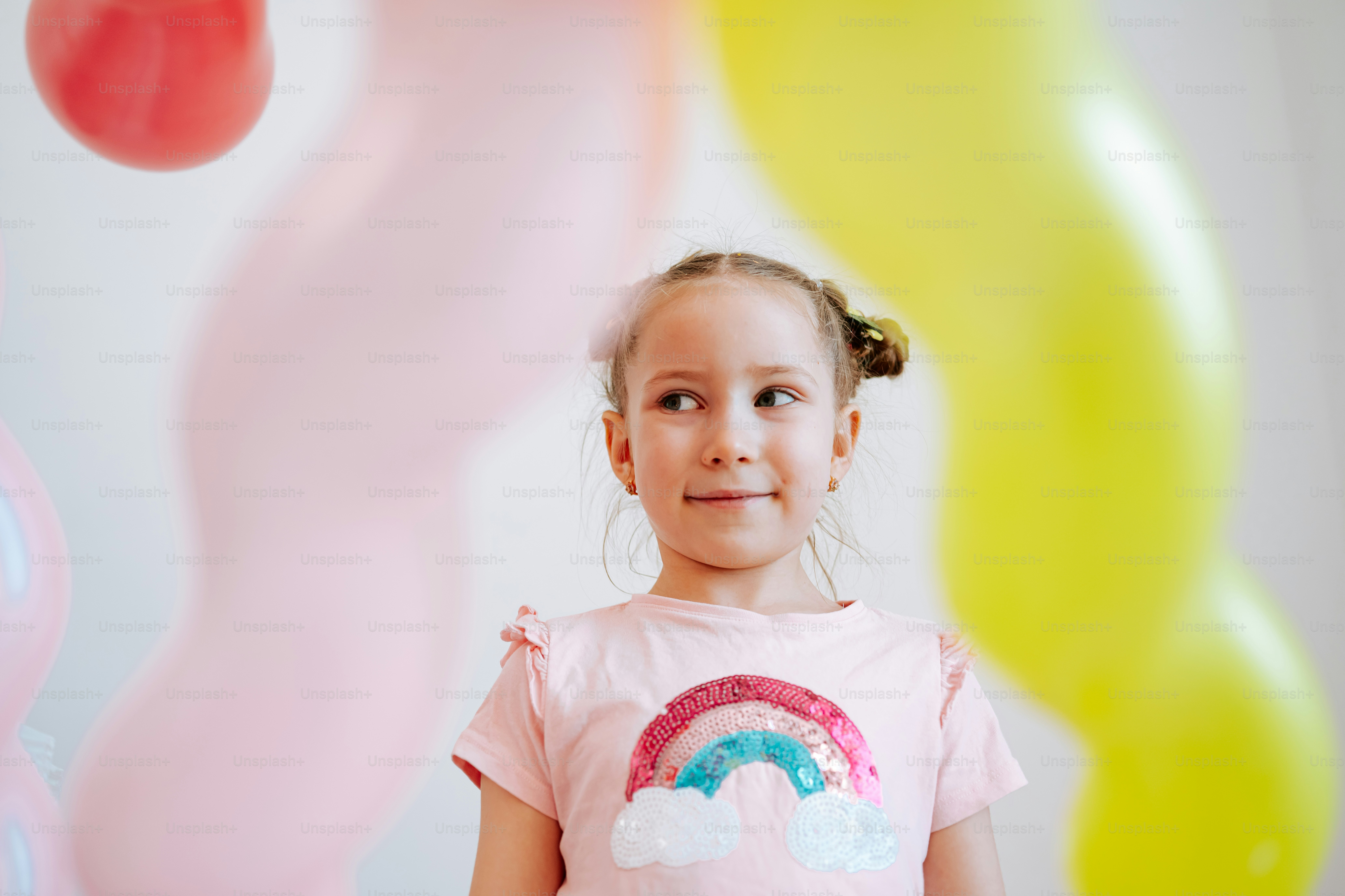 Young girl in a rainbow shirt with balloons