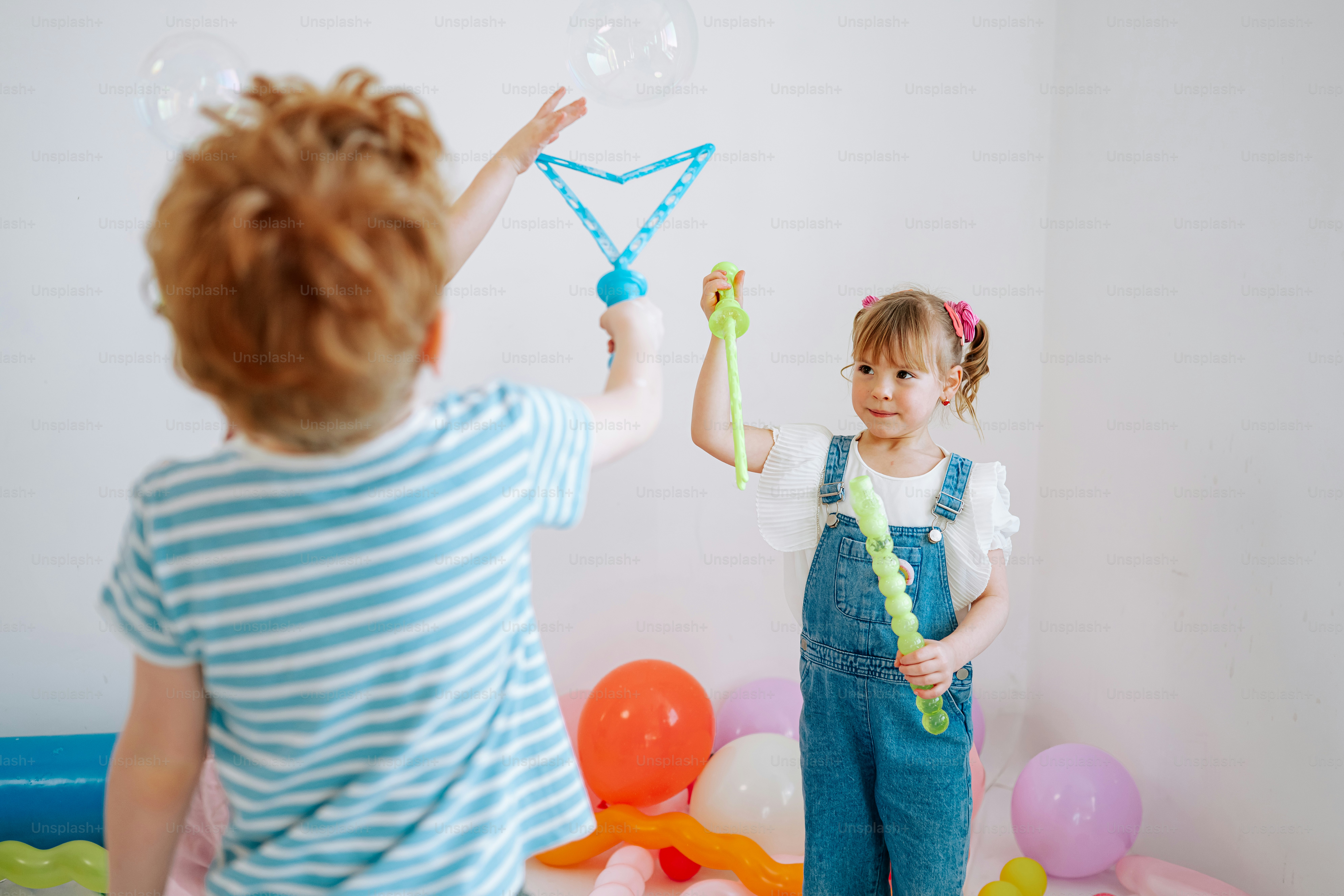 Two children blowing bubbles indoors with bubble wands. photo – Girl ...