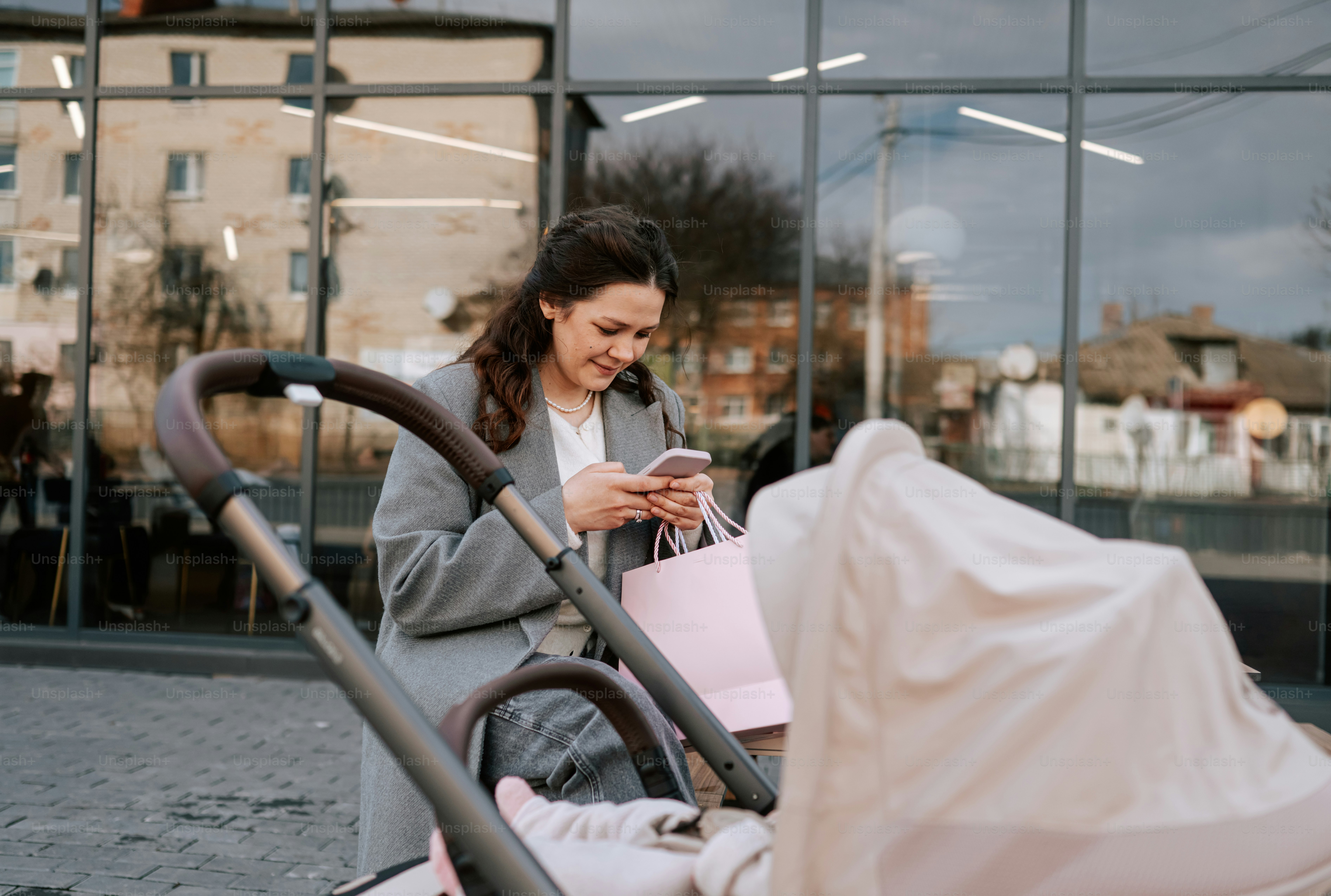 Woman with stroller checks phone outside building