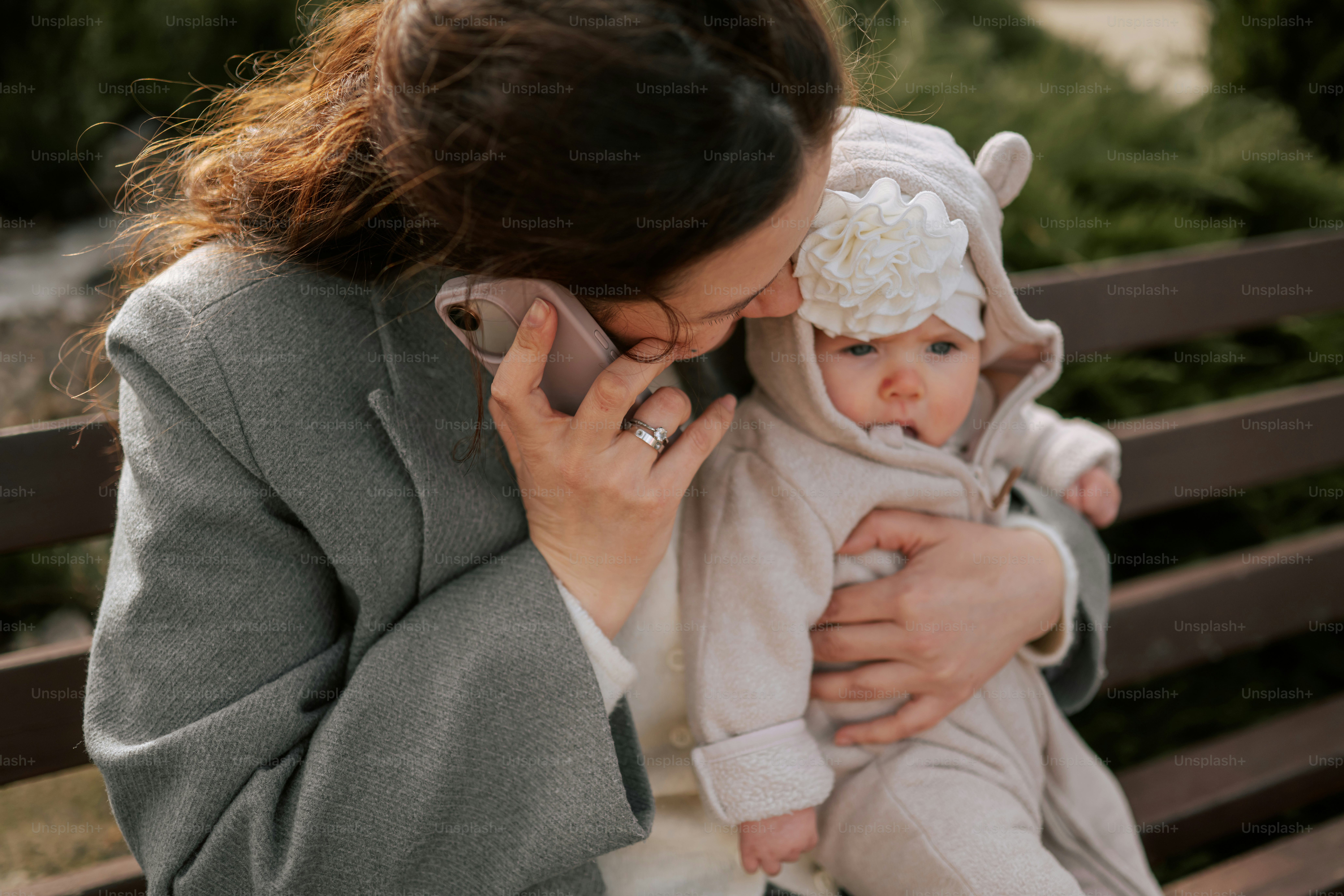 Mother holding a baby while talking on the phone