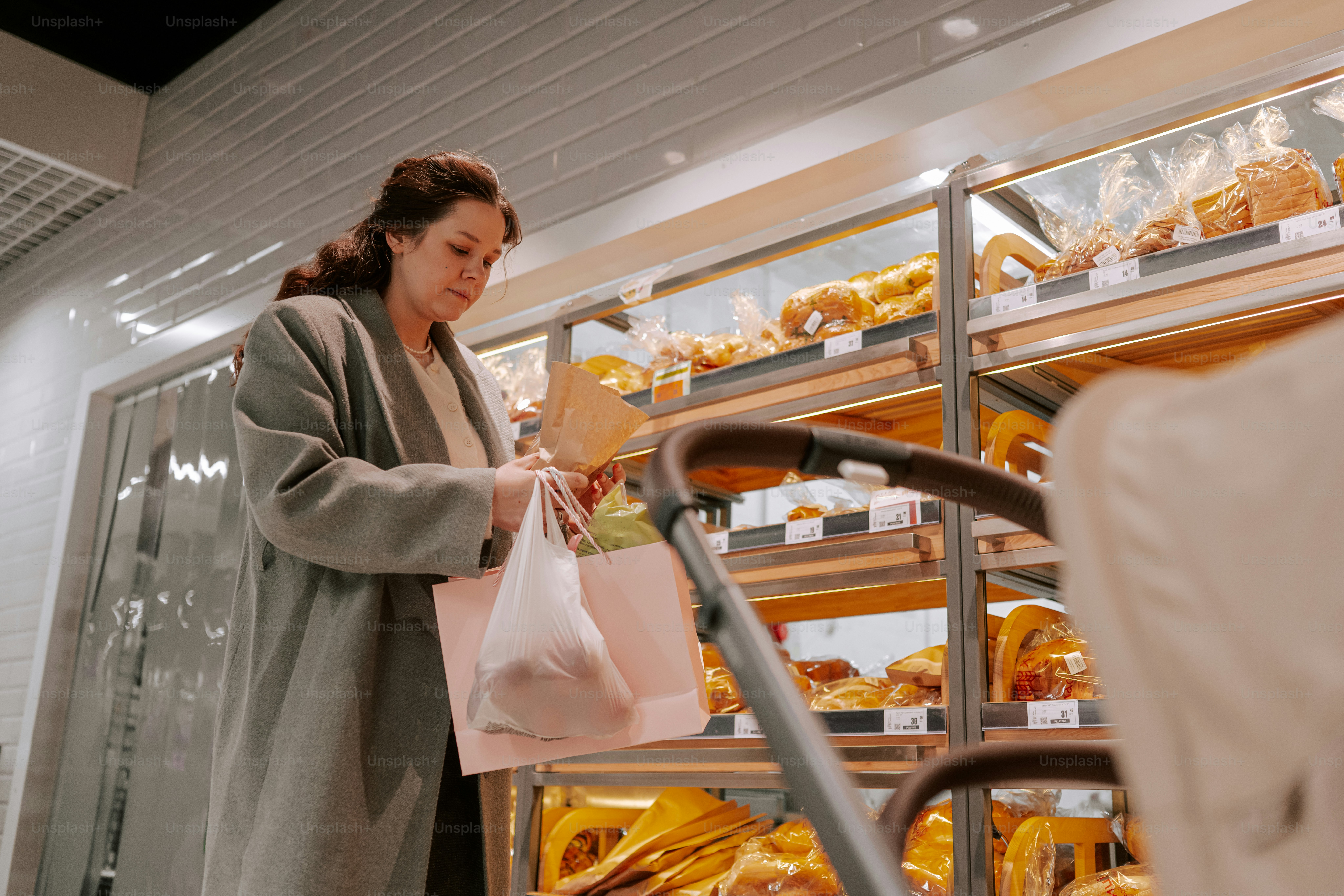 Woman shopping for baked goods with a stroller.