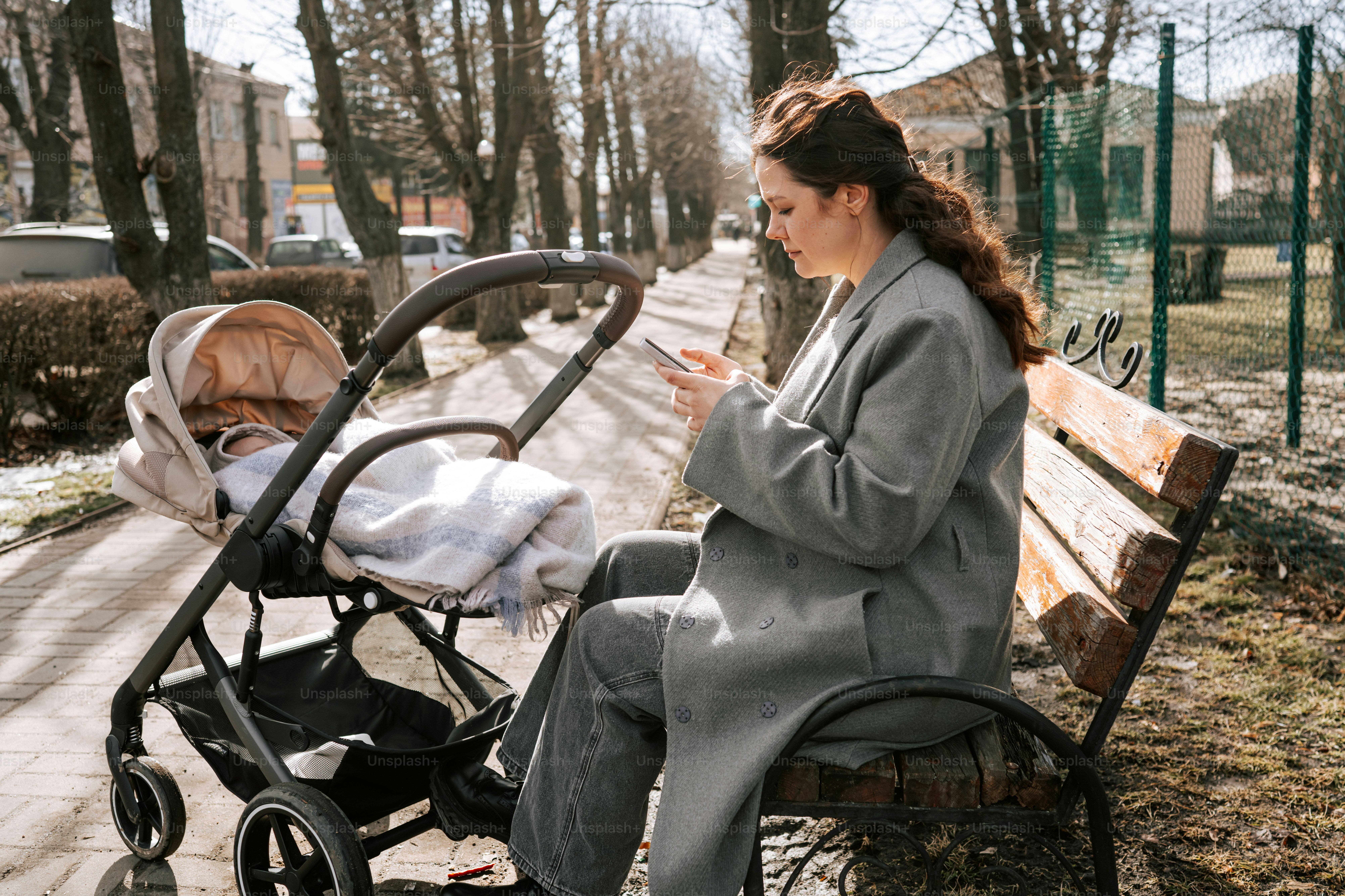 Woman sitting on a park bench with a stroller