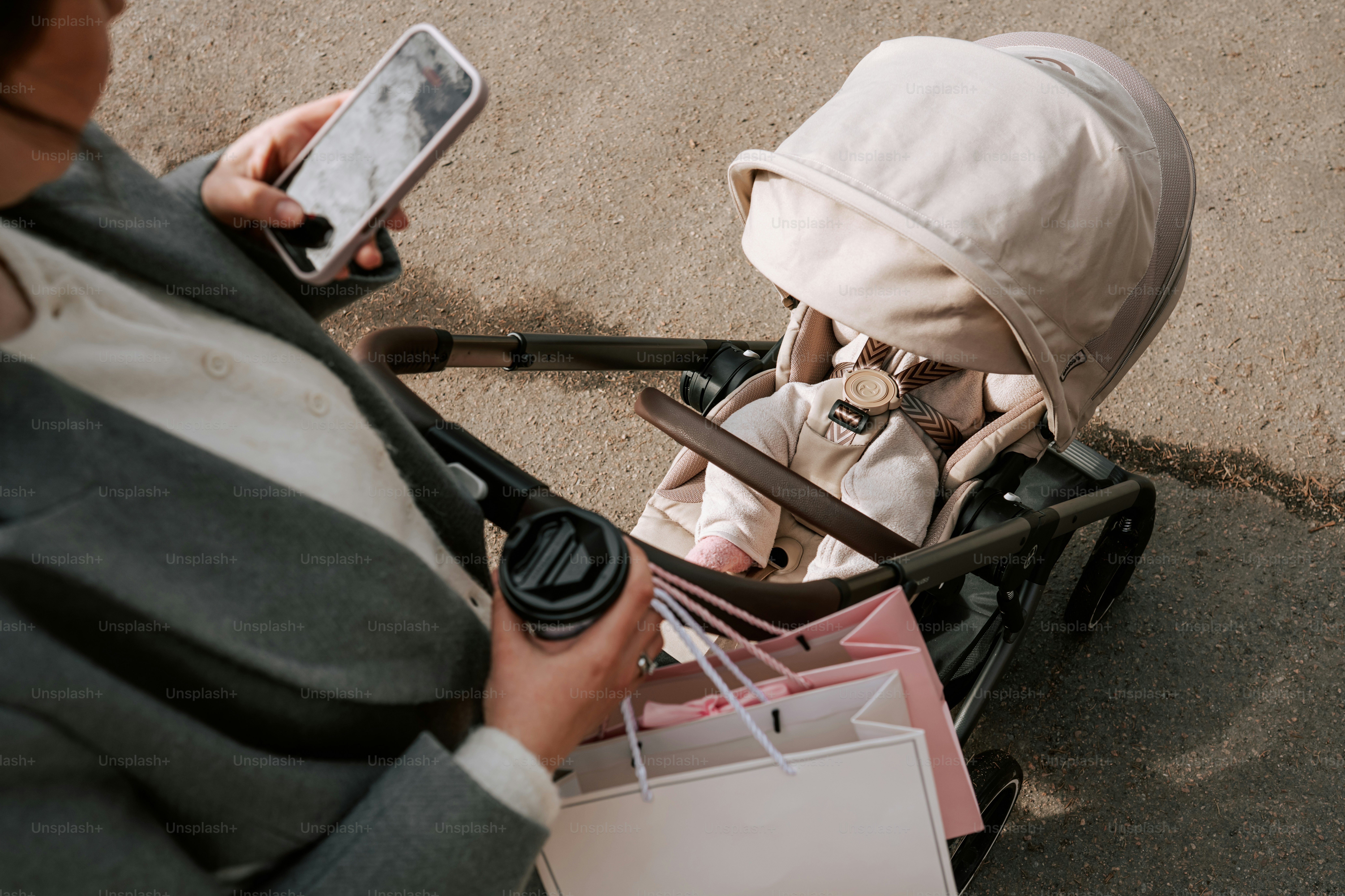 Woman with coffee and phone beside baby stroller