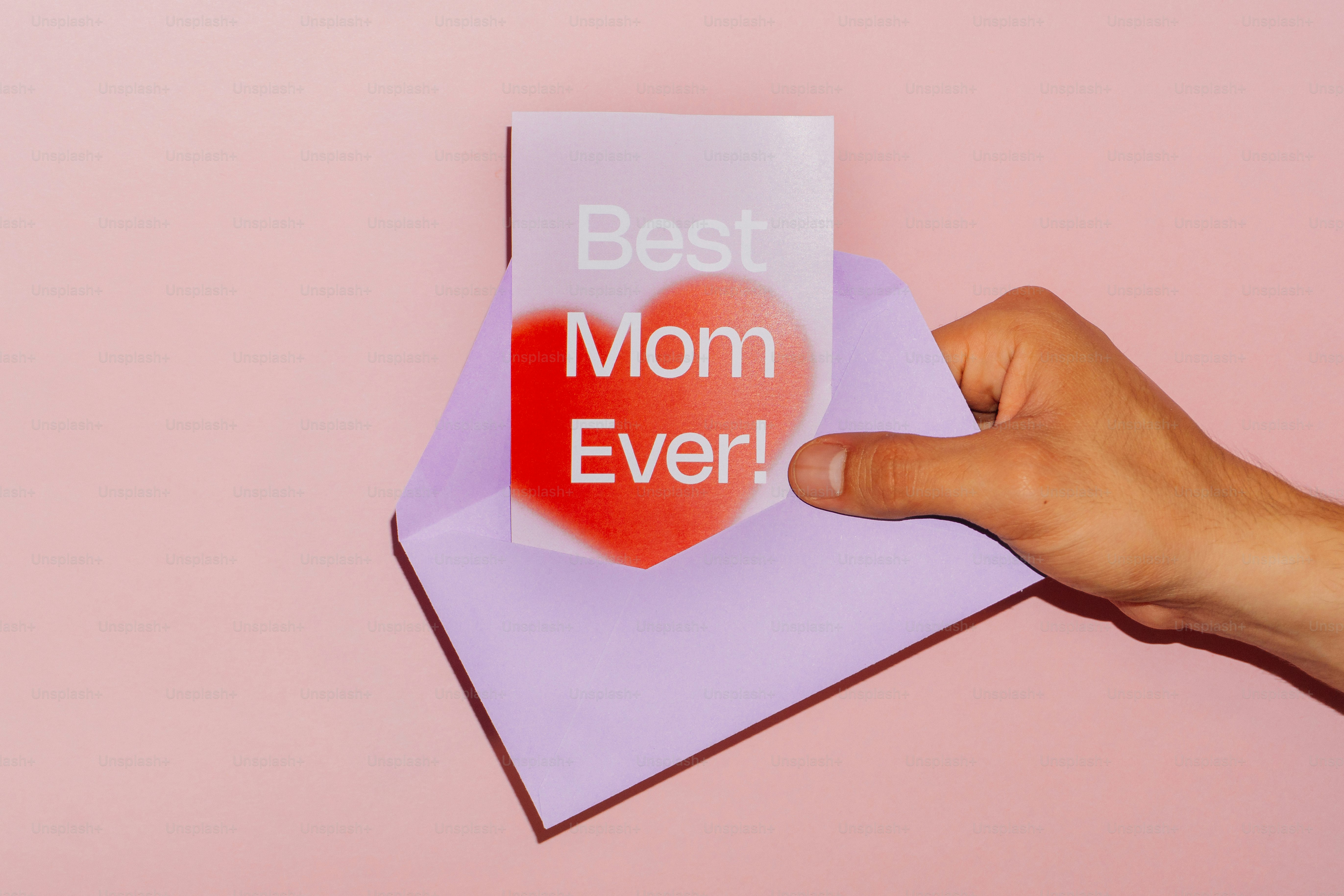 Sosteniendo una tarjeta en un sobre que dice 'mejor madre del mundo'