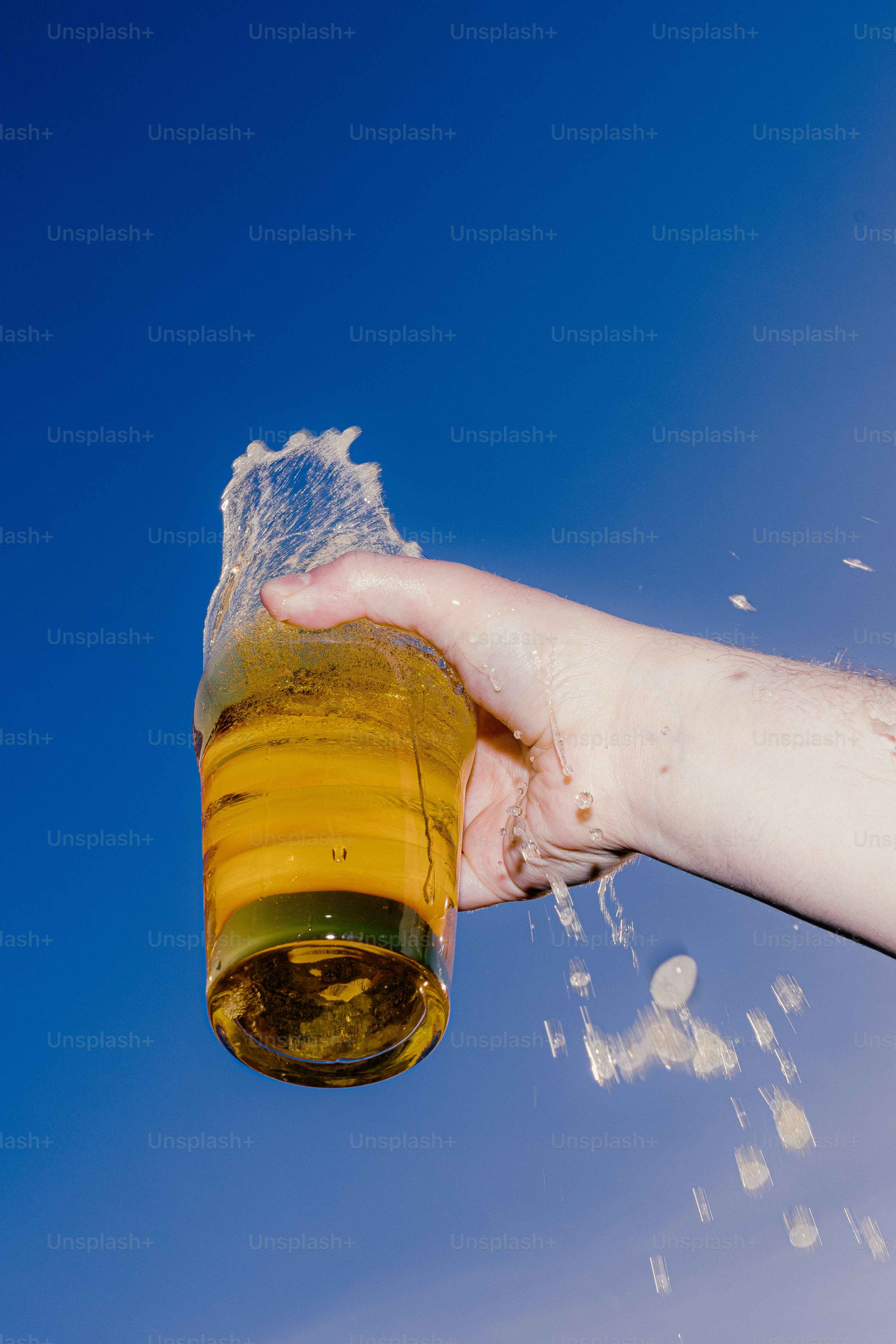 Mano sosteniendo un vaso de cerveza con líquido salpicando.