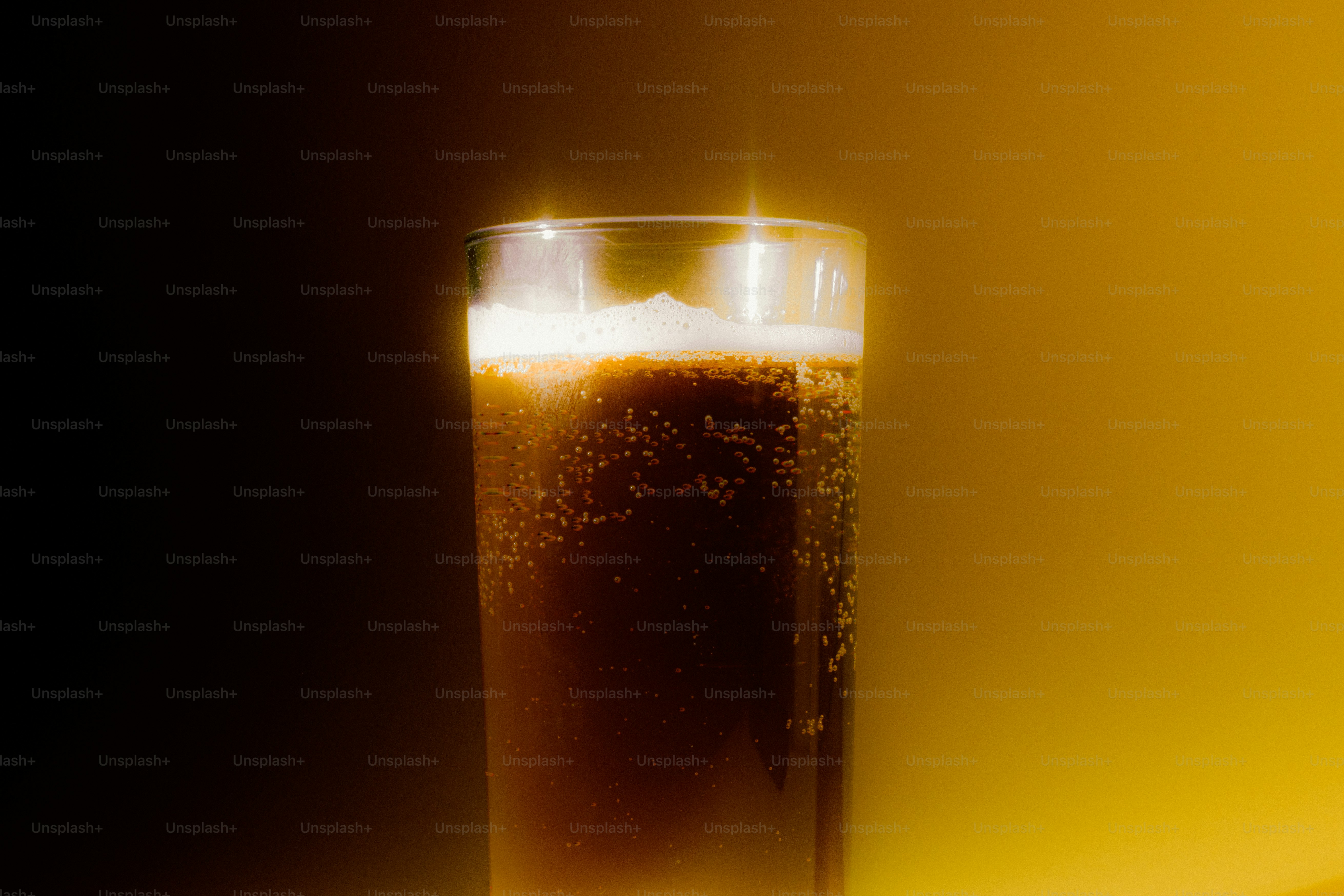 Un vaso de refresco oscuro con espuma y burbujas