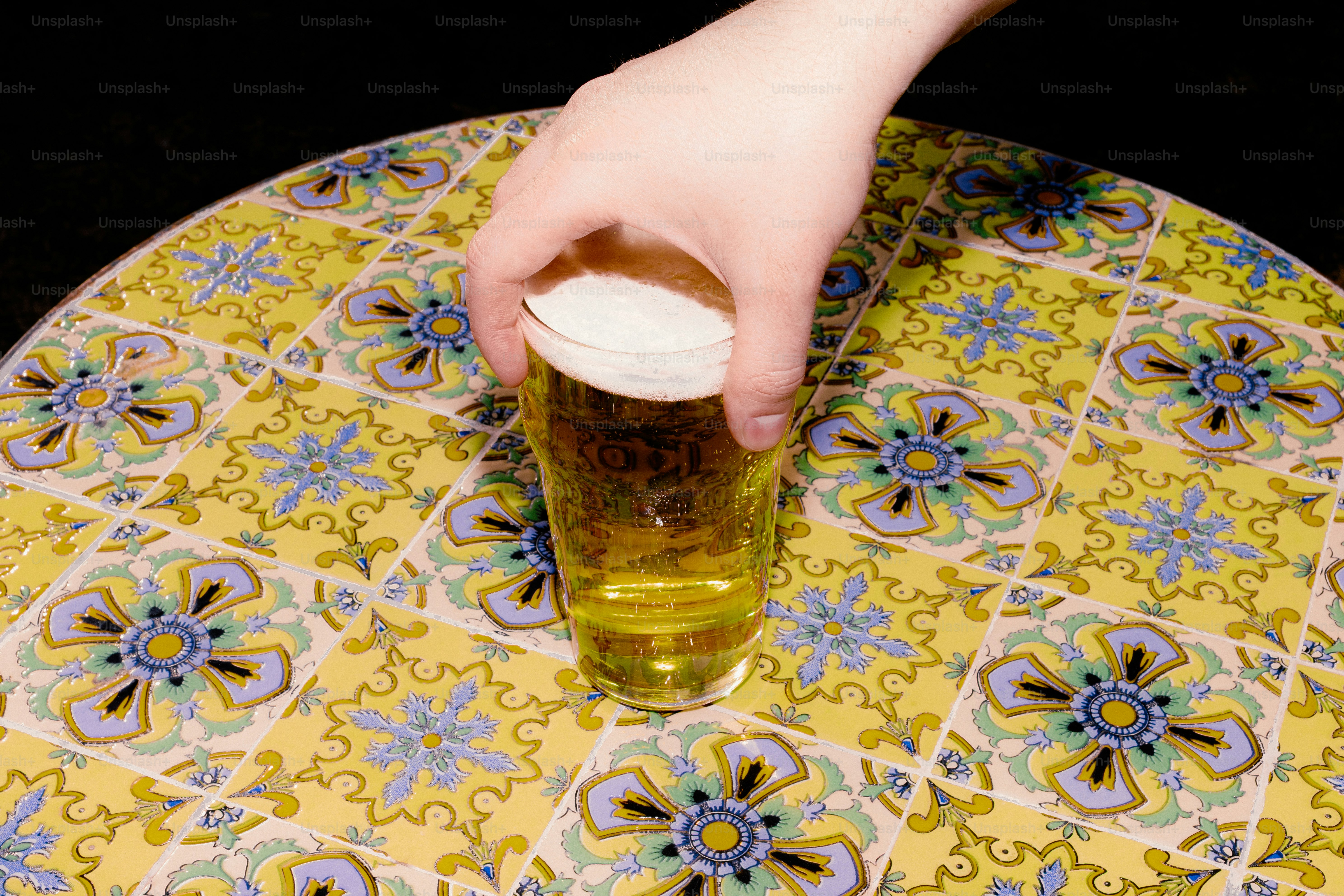 Hand reaching for a beer on a patterned table