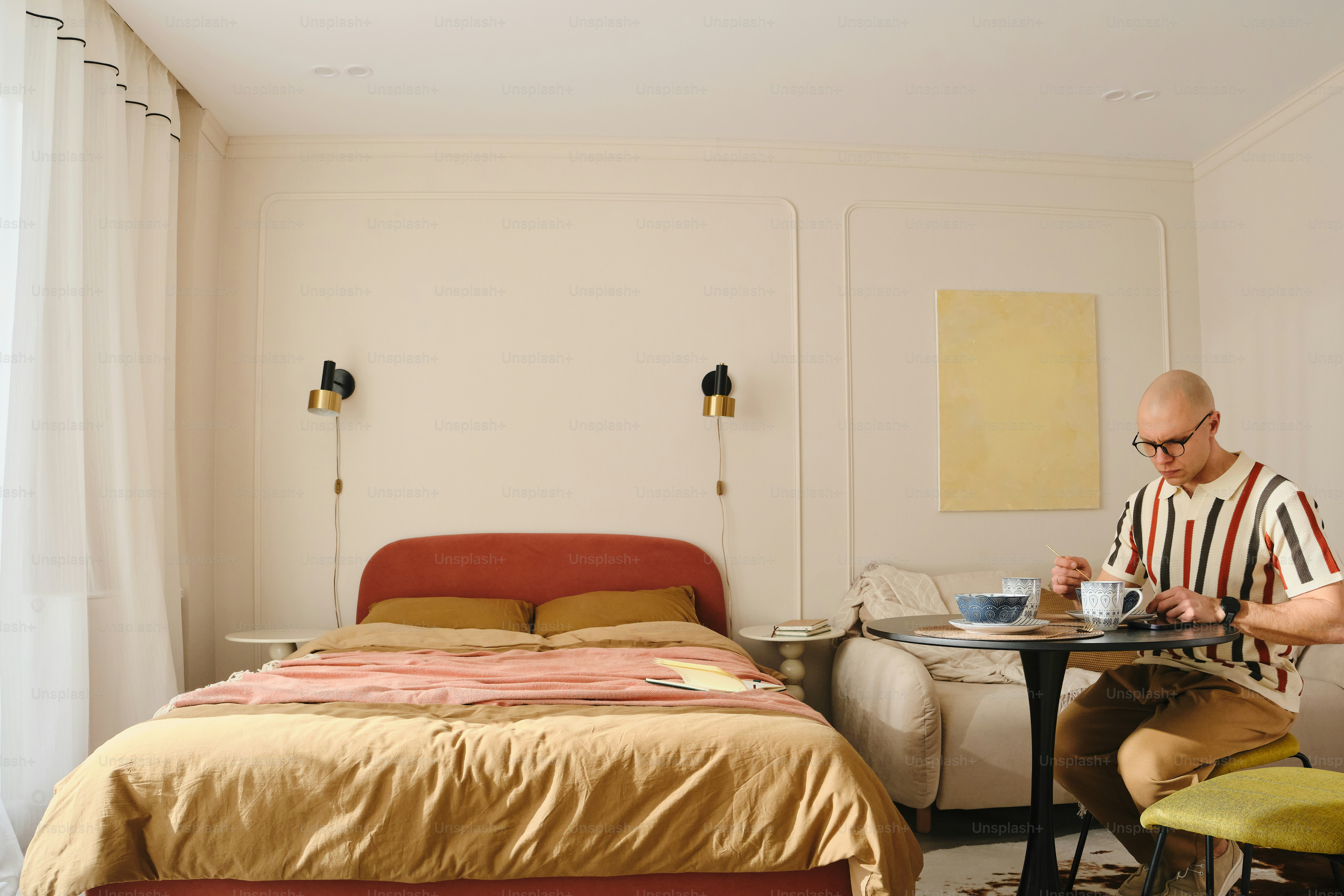 Man eating at a small table in a hotel room.