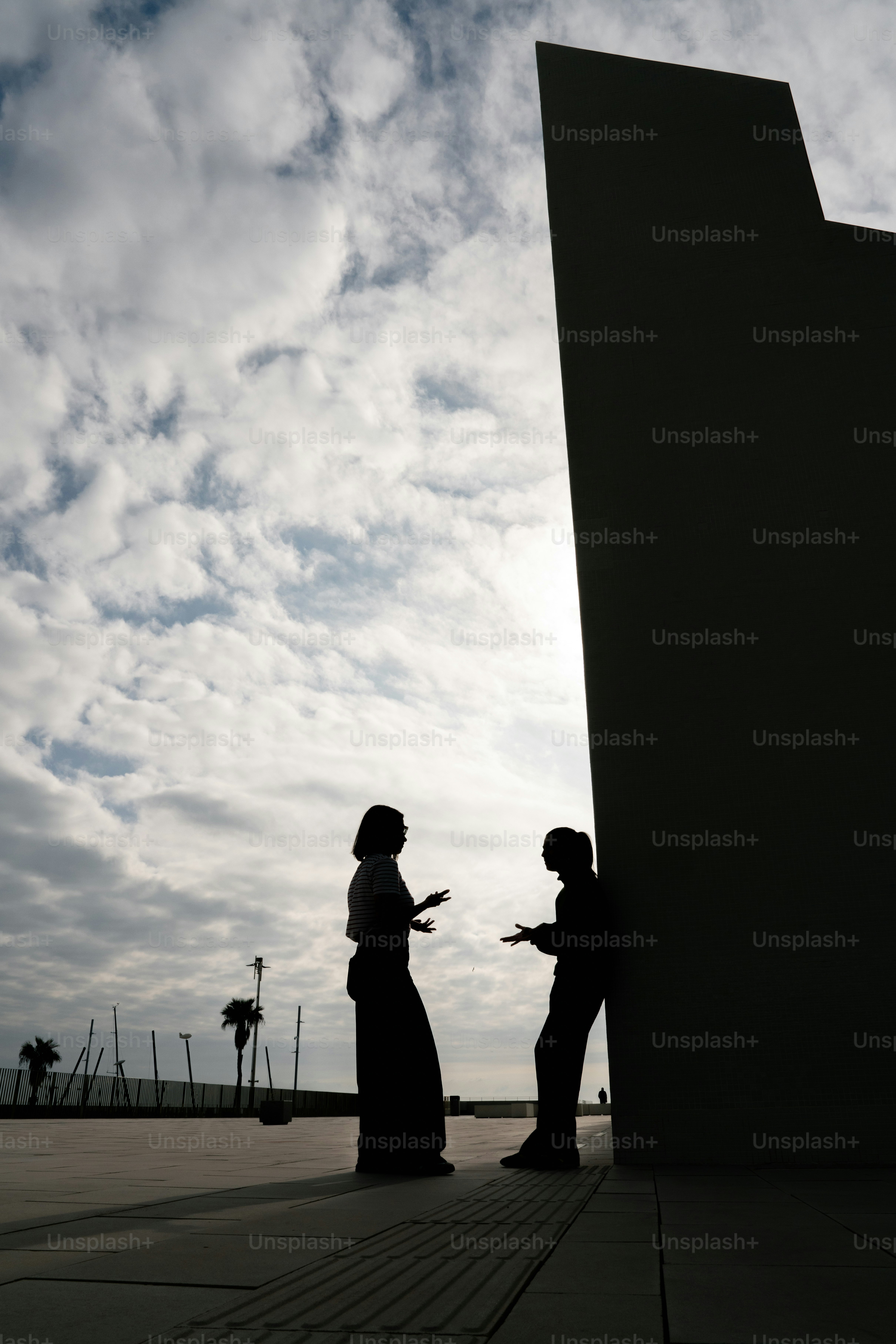 건물 옆에서 대화하는 두 사람의 실루엣이 보인다