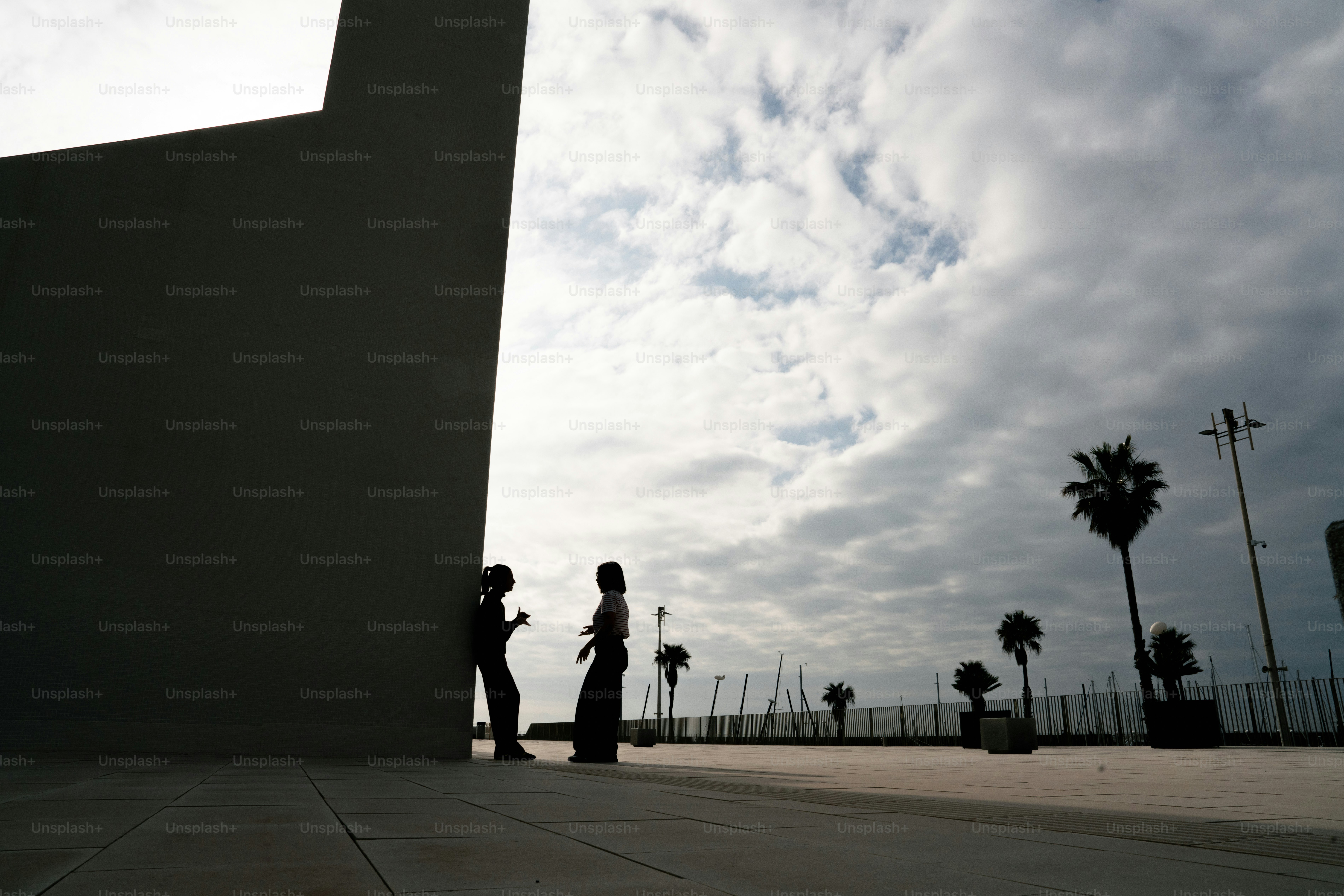 야자수 벽 옆에서 이야기하는 두 사람이