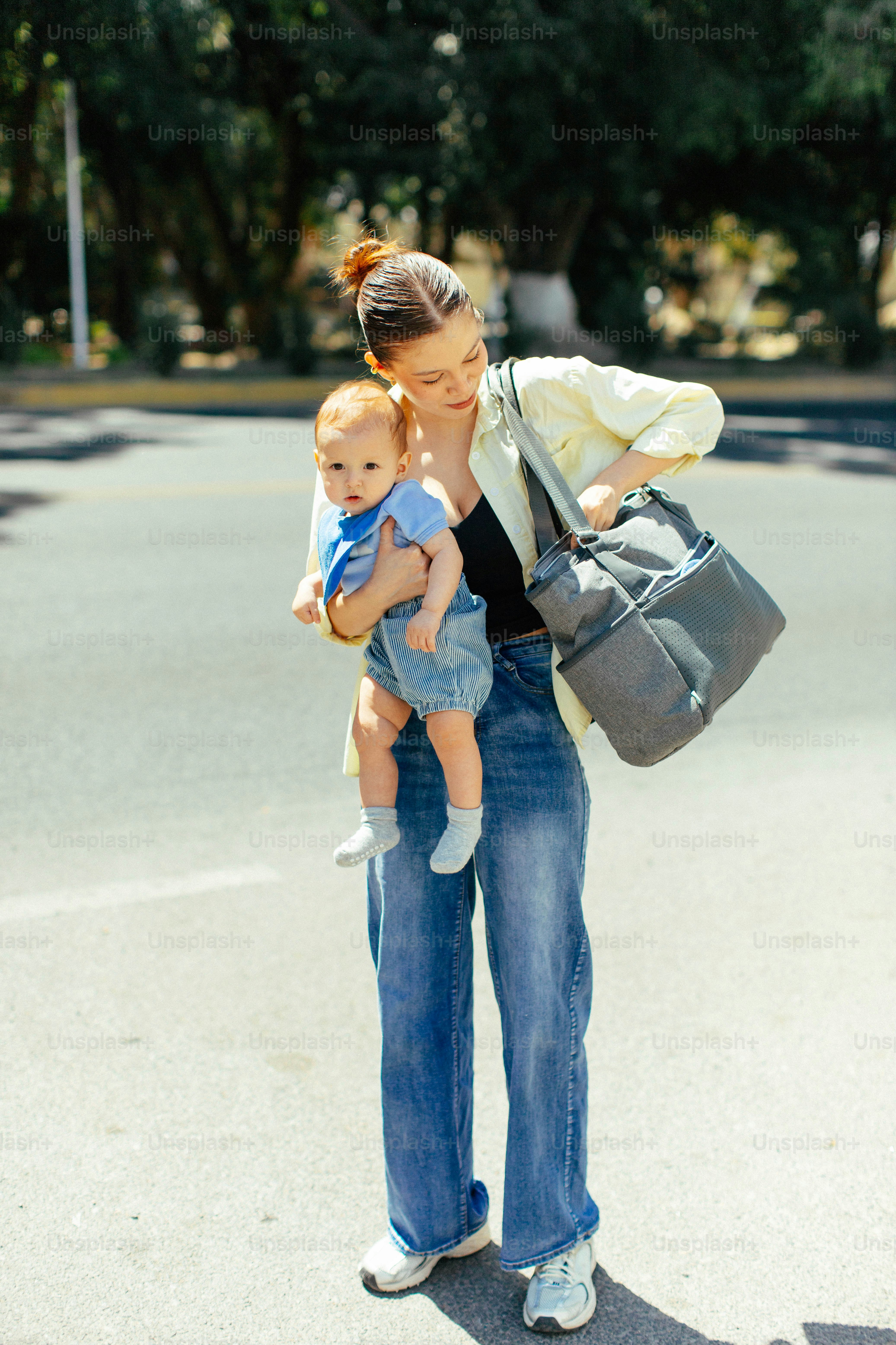 Madre sosteniendo a su bebé mientras lleva una bolsa