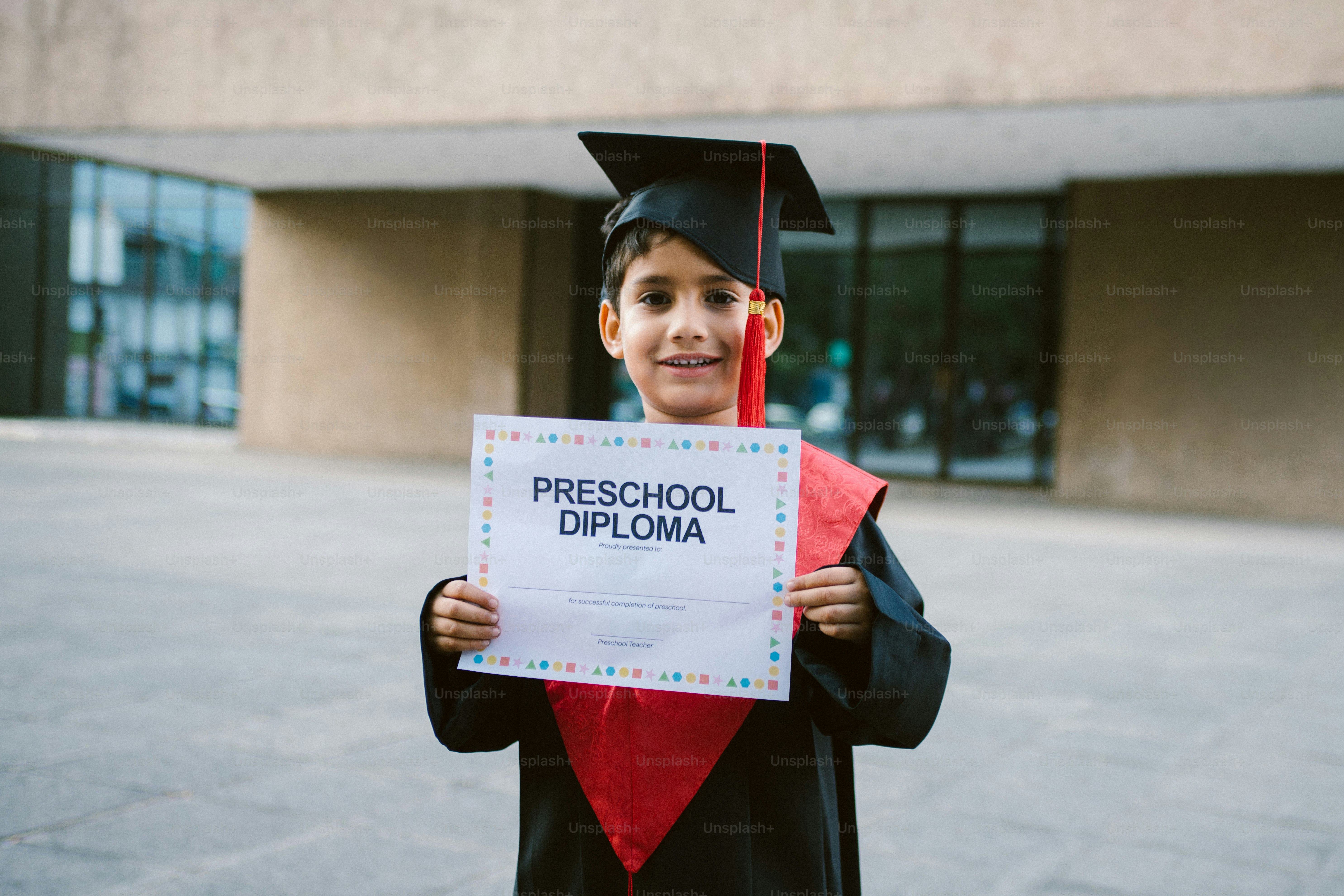 A smiling child in a graduation cap holds a diploma. photo – Education ...